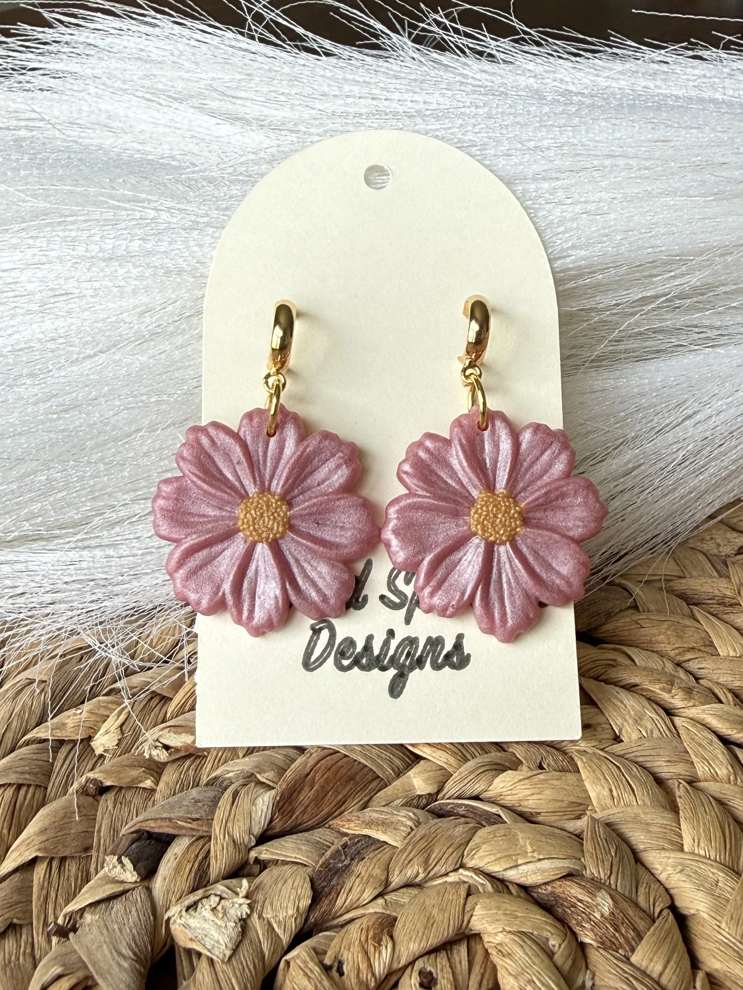 Pink flower-shaped earrings with gold accents on a white card that reads 'L Style Designs,' placed on a woven wicker surface.