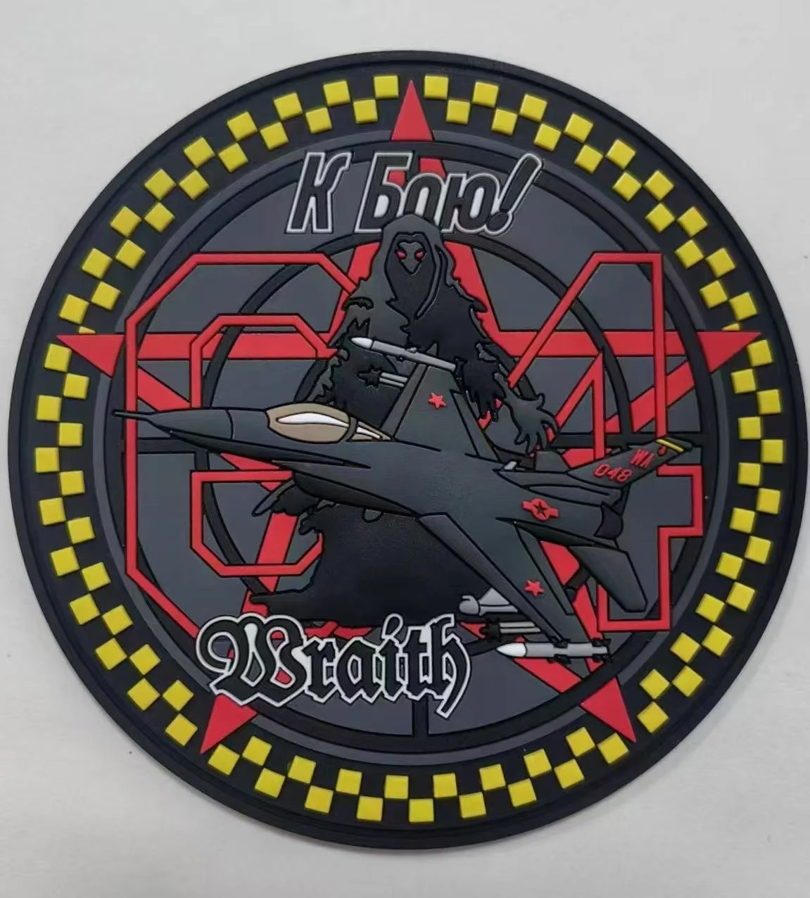A circular patch featuring a fighter jet, a dark figure with a hood, and Russian symbols. The patch has yellow and black checkered border with red stars and Cyrillic text.