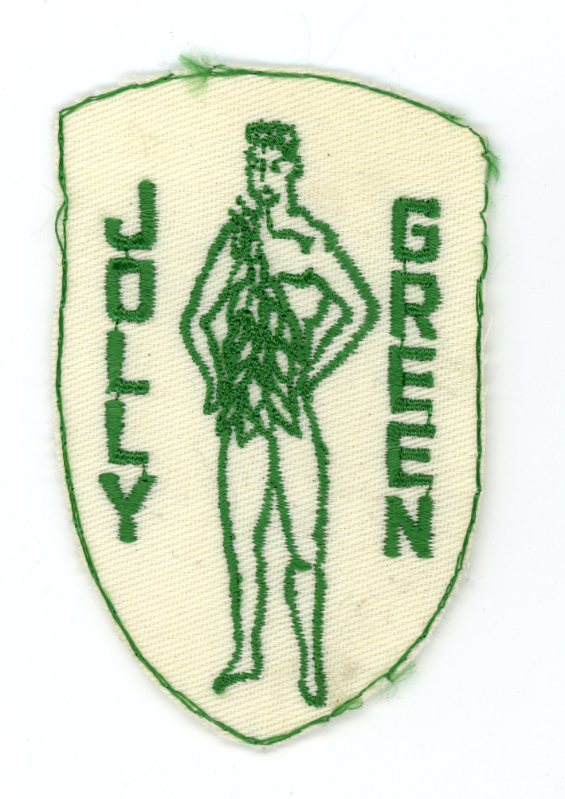 A green embroidered patch shaped like a shield with a stick figure of a person with leafy vest in the center, and the words 'JOLLY GREEN' stitched vertically on either side.