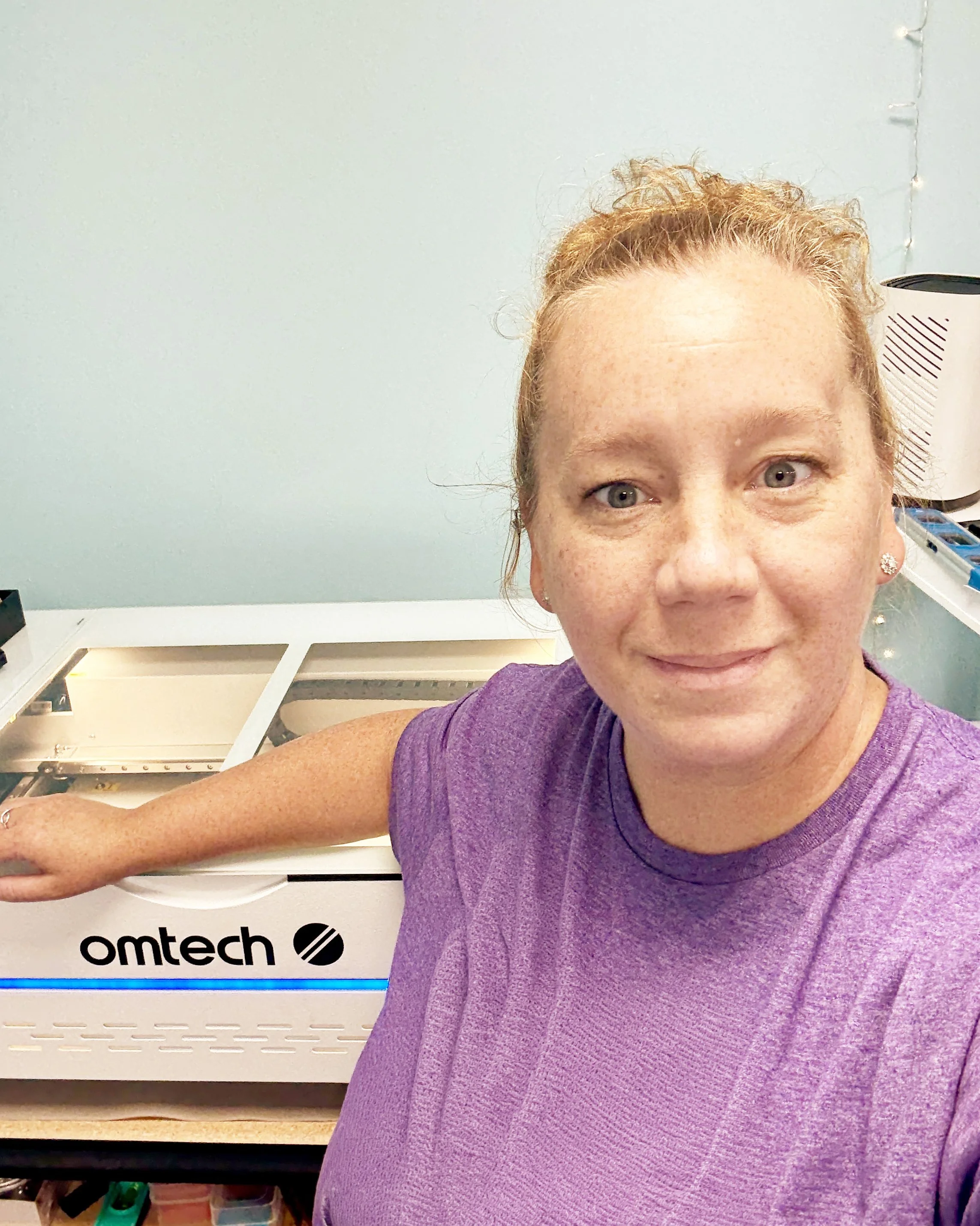 Christy, owner of Knotty Laser in Panama City, FL, operating a professional laser engraver for custom wood and acrylic projects.