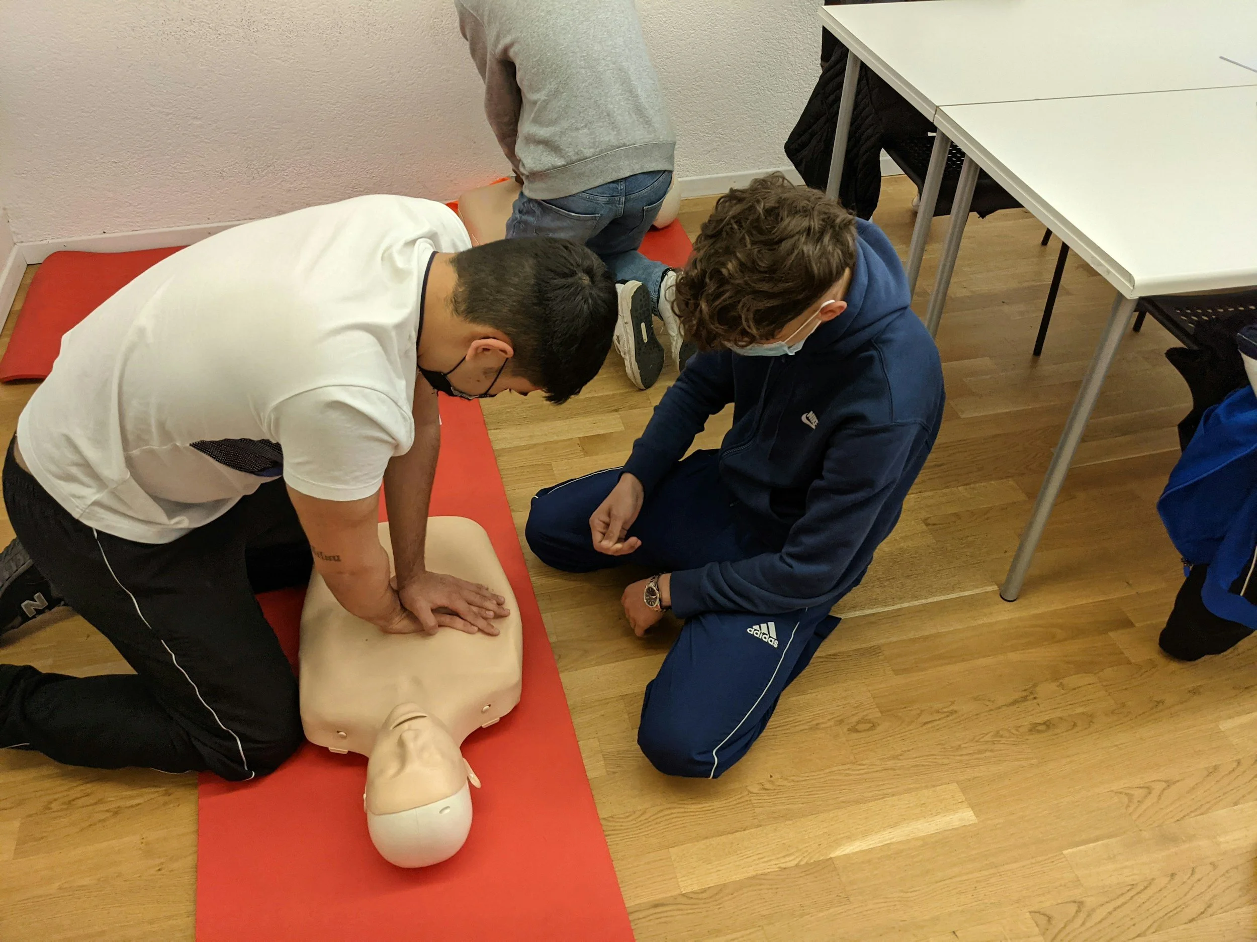 3 young boys learning CPR and rescue breaths on a training mannikin