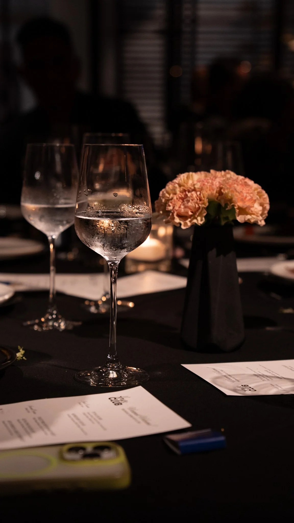 Formal event photography. An image showing dimly lit dining table with three wine glasses.
