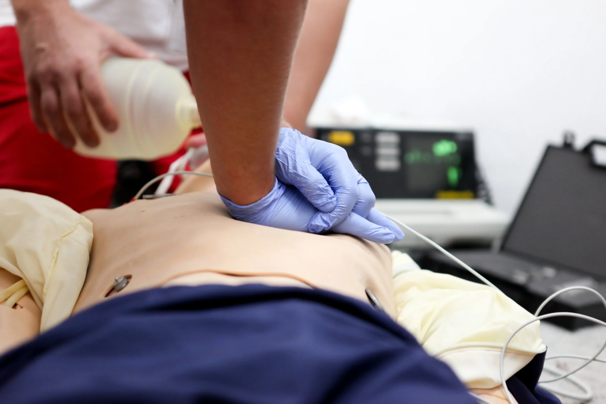A medical professional wearing gloves administering chest compressions to a patient during a medical emergency training or procedure.