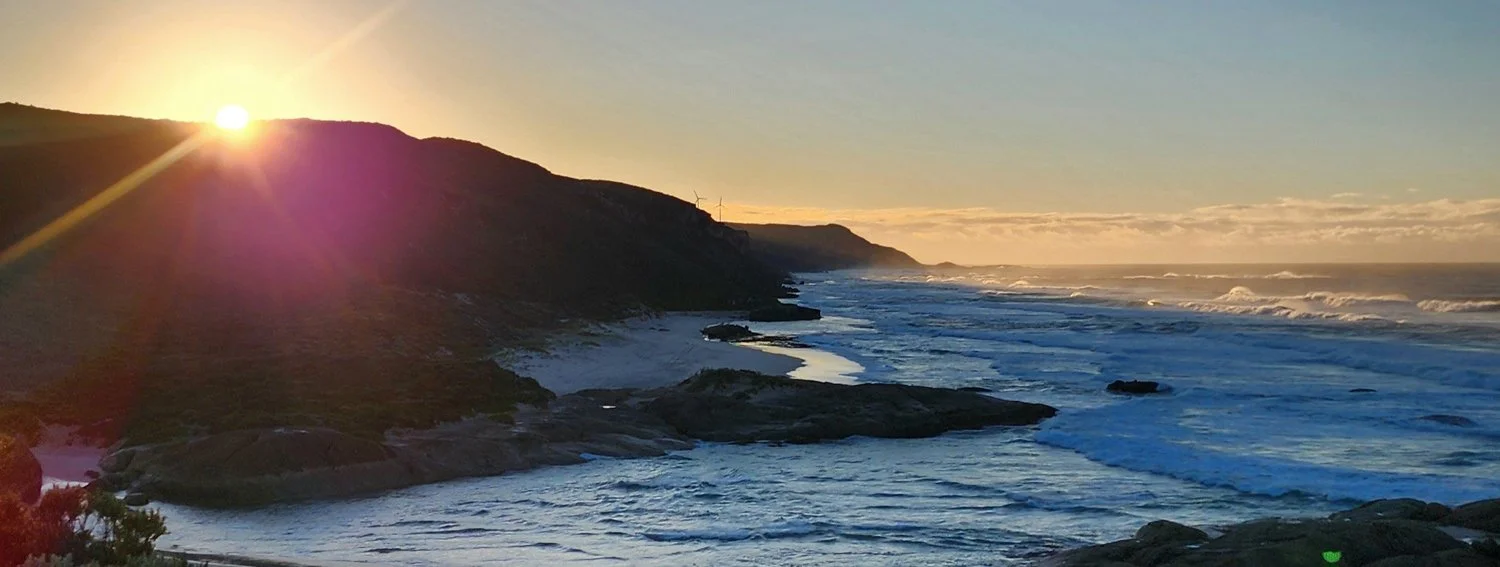 Coastal cliffs and ocean illuminated by warm evening light in the Great Southern.