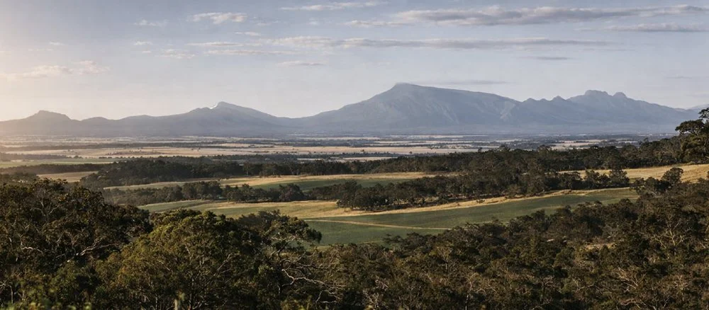 View across the Porongurup countryside towards the Stirling Range beneath a cloudy sky.