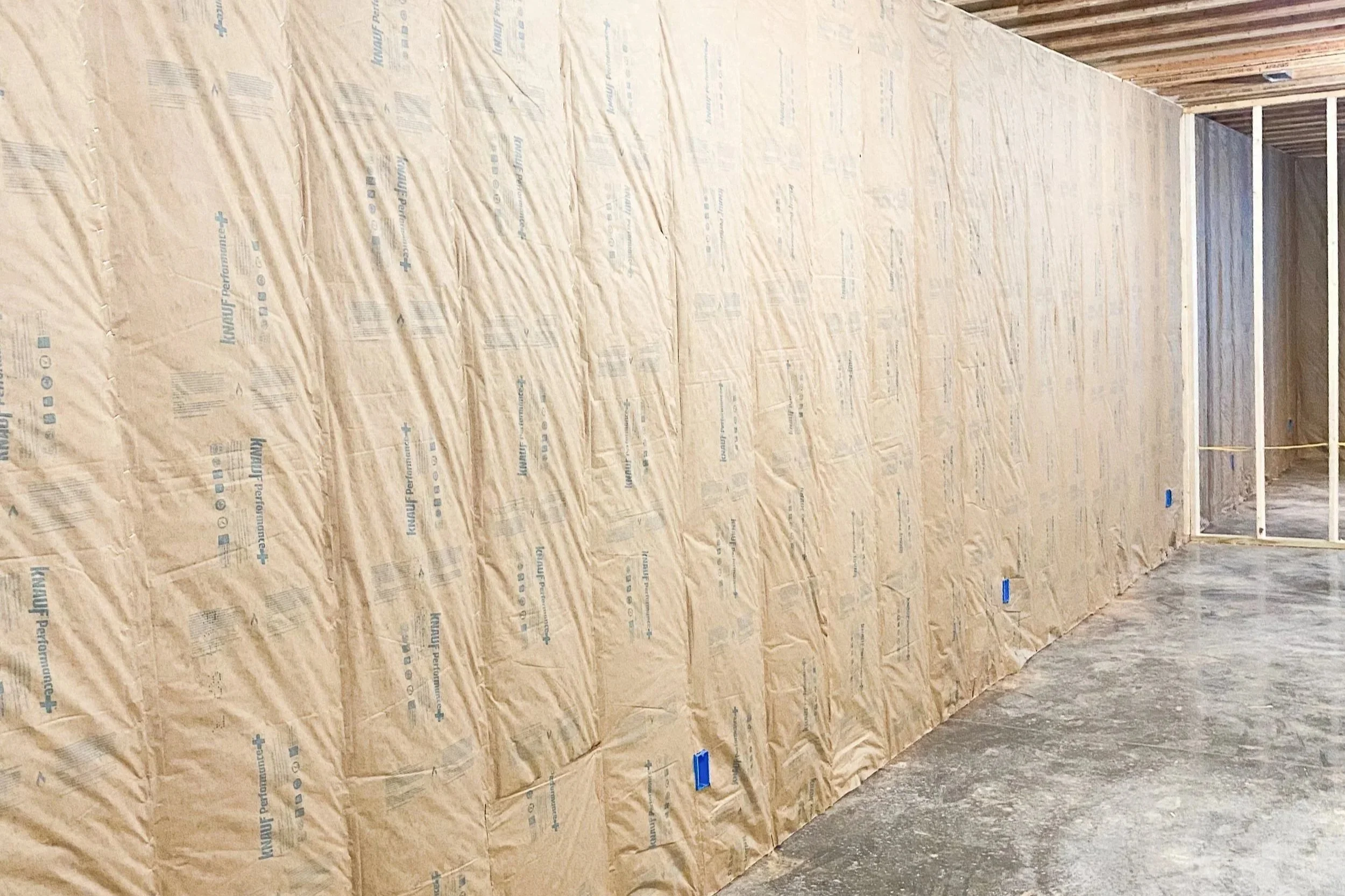 Partially constructed interior wall with insulation and framing in a building under construction.
