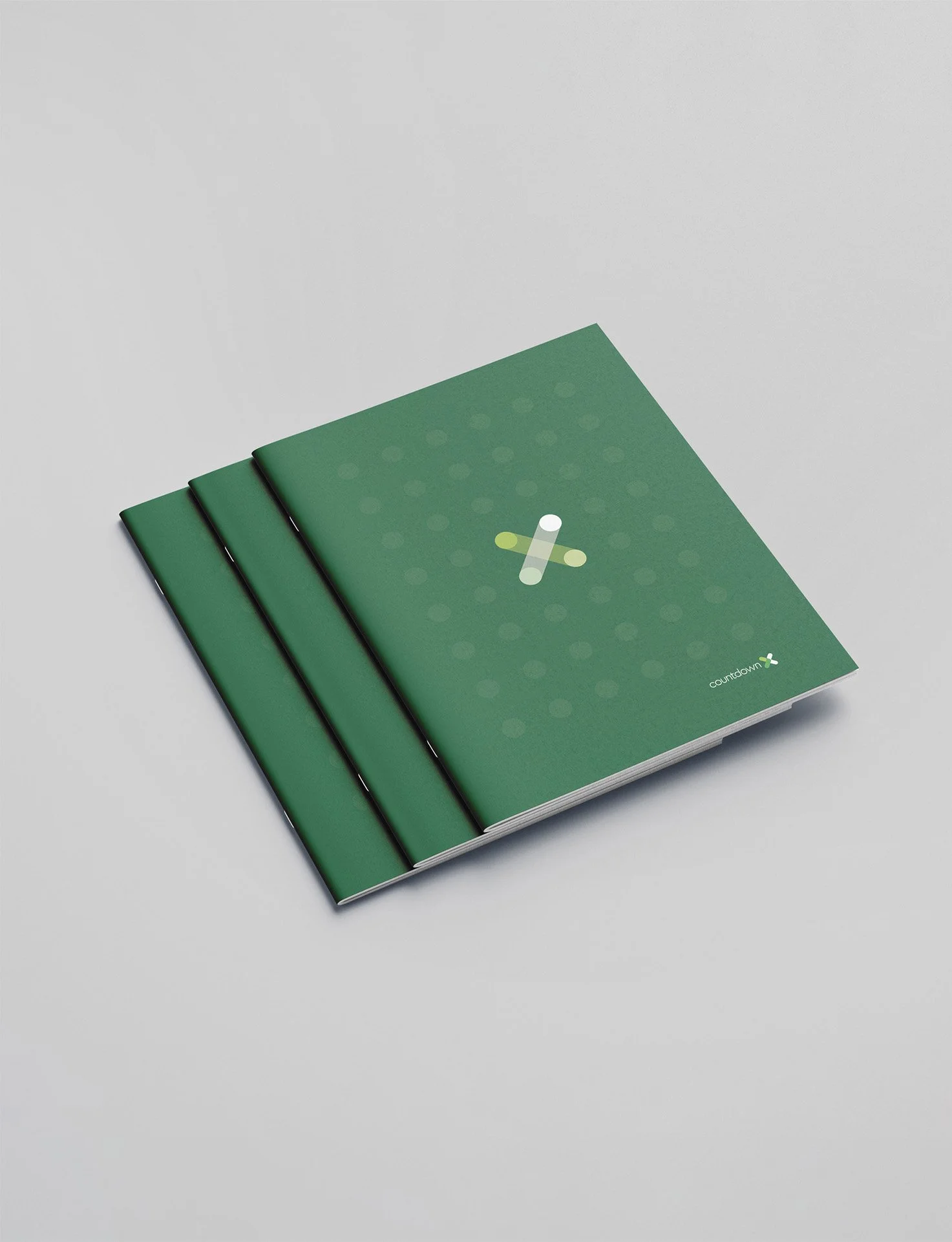 Three green booklets with a green cover, featuring a white and yellow medical cross symbol and the 'Countdown' logo on the bottom right corner, stacked on a white surface.