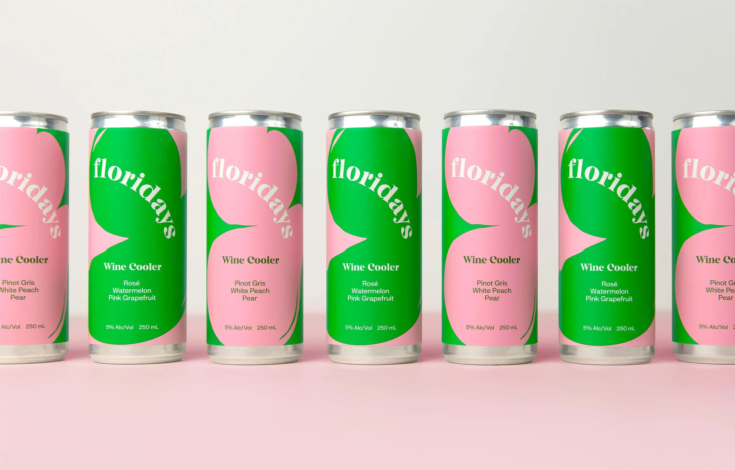 Seven cans of wine cooler arranged in a row on pink background, alternating pink and green labels with the word 'floridays' and flavors listed.
