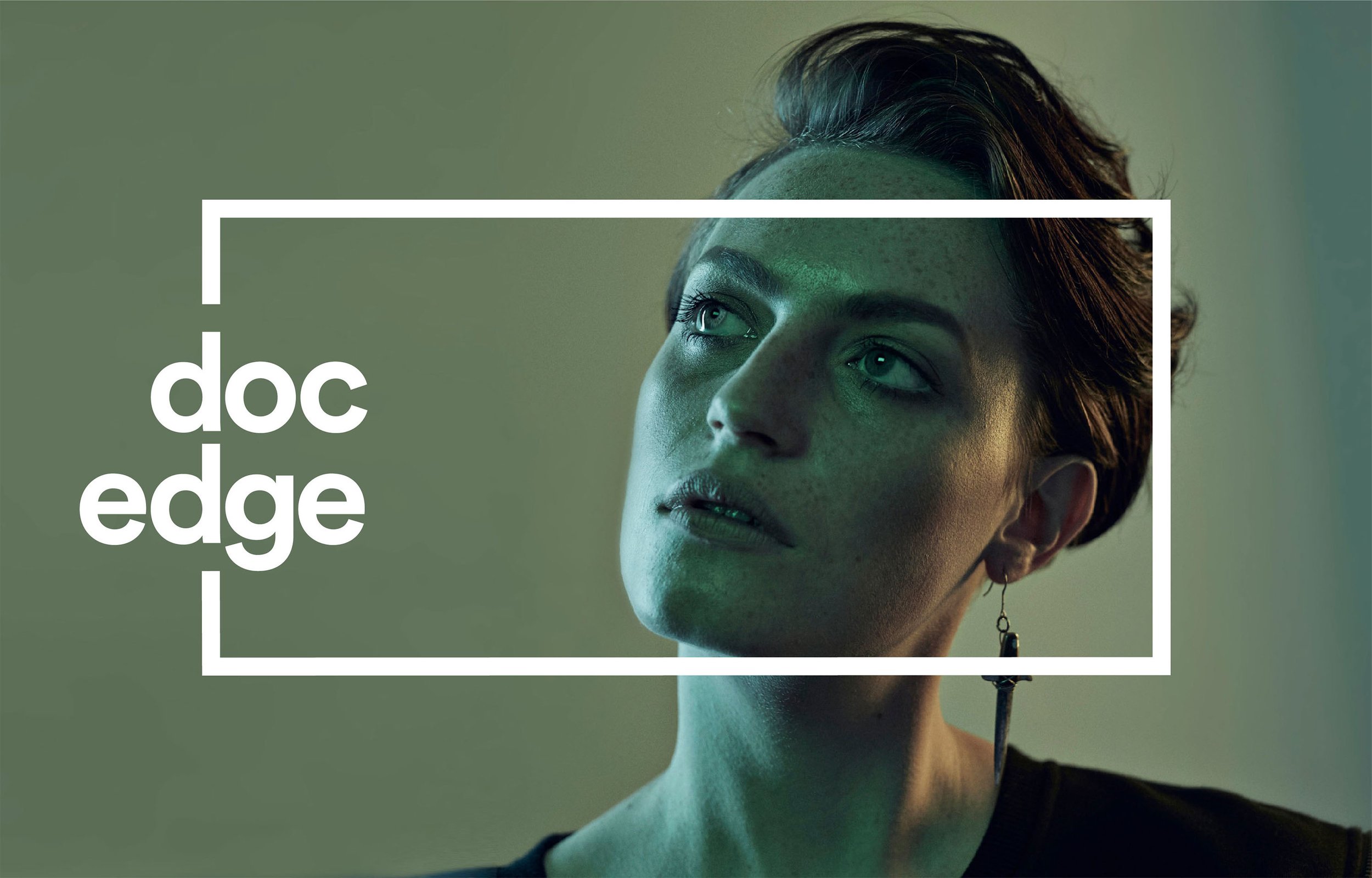 Close-up of a woman with short hair, green eyes, and a serious expression, with a green tint and a white rectangular overlay containing the text 'doc edge'.