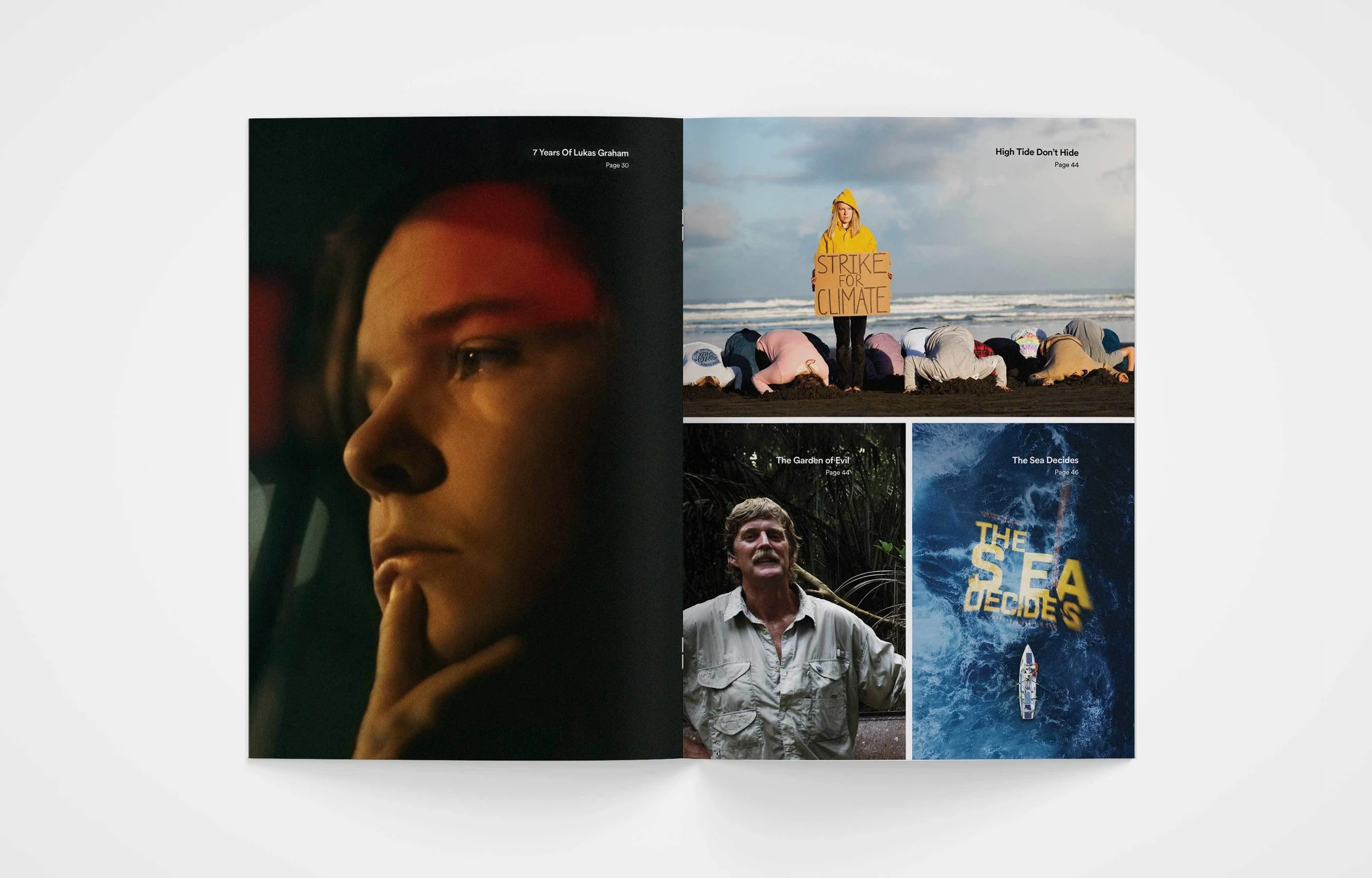 Open magazine displaying four pages with various photographs and text. The left page shows a close-up of a person's face with a contemplative expression. The top right page features a woman in a yellow raincoat holding a sign that reads 'Strike for Climate,' with people bowing on a beach behind her. The bottom right page is divided into two sections: the left shows a man in a jungle with a distressed expression and the right displays a boat in the ocean with overlaid text reading 'The Sea Decides.'
