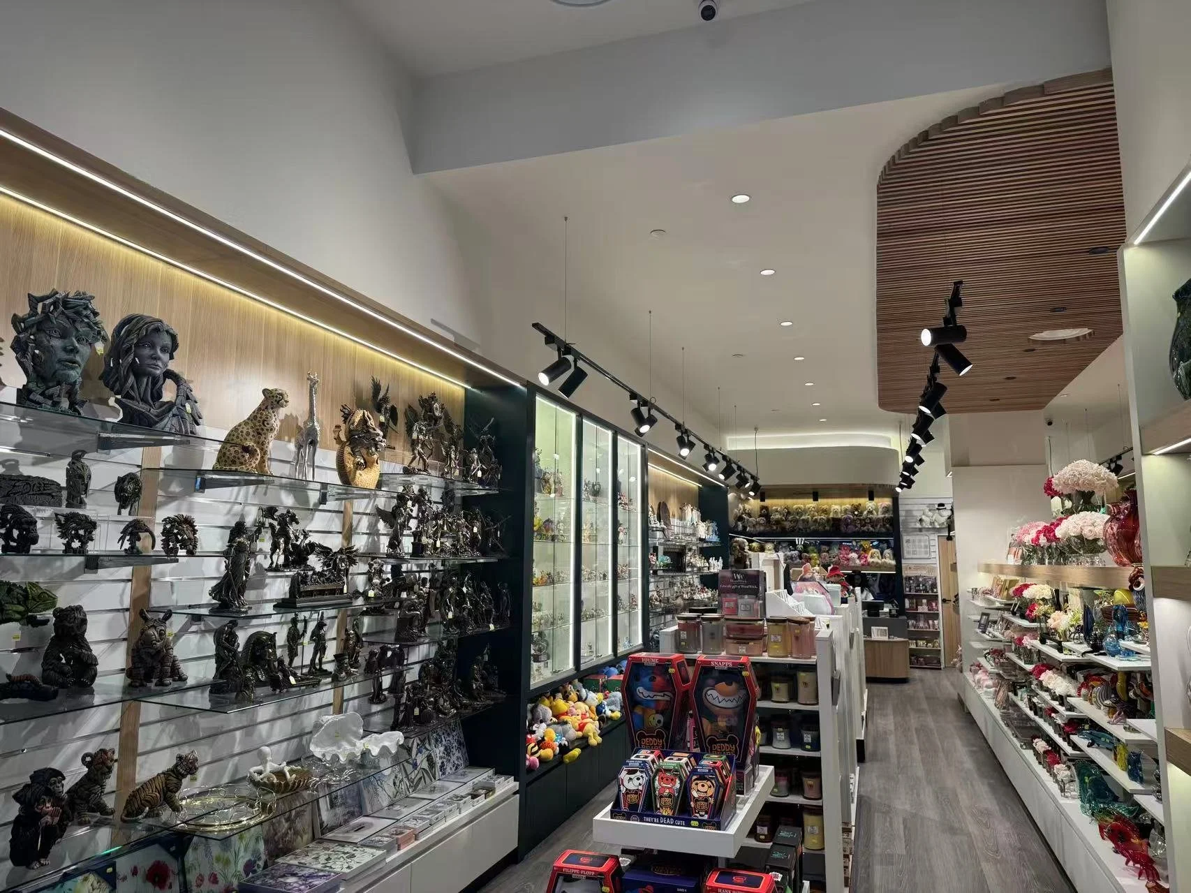 Interior of a gift shop with shelves displaying various decorative items, including figurines, plush toys, flowers, and accessories.
