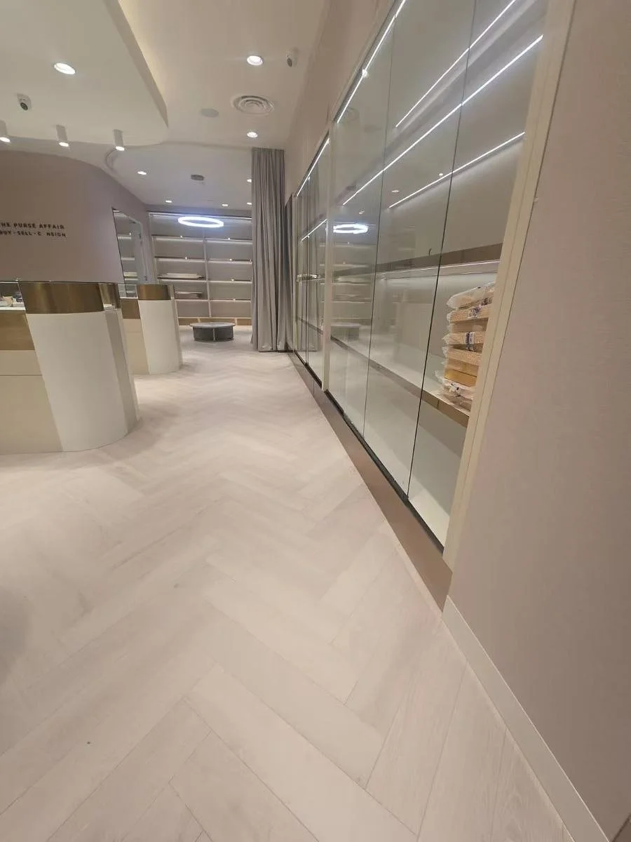 Empty retail or display area with glass shelves on the wall, light-colored flooring, and modern lighting in a store or showroom.