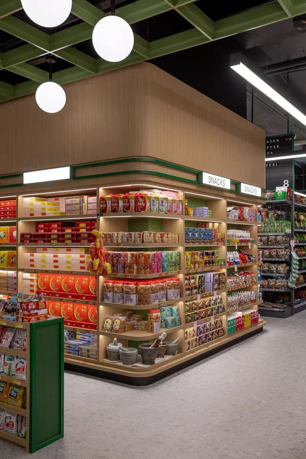 Grocery store section labeled 'Snacks' with shelves stocked with various packaged snacks and confections, in a modern store interior.