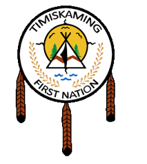 Emblem of the Timiskaming First Nation featuring a circular design with a central green and yellow landscape, a teepee, and two crossed sticks, surrounded by a white background with black text and brown hanging tassels.
