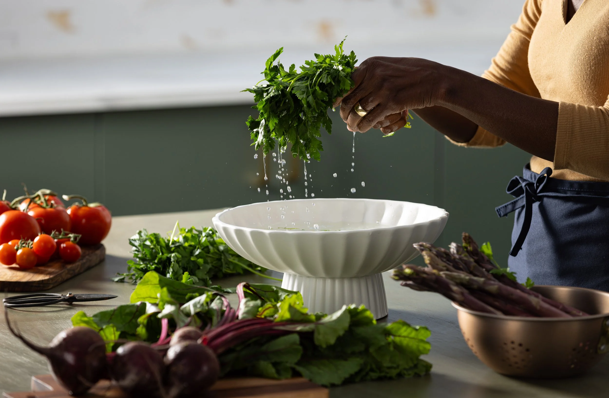 Lifestyle photograph displaying a woman preparing some produce to be cooked in photography studio kitchen.
