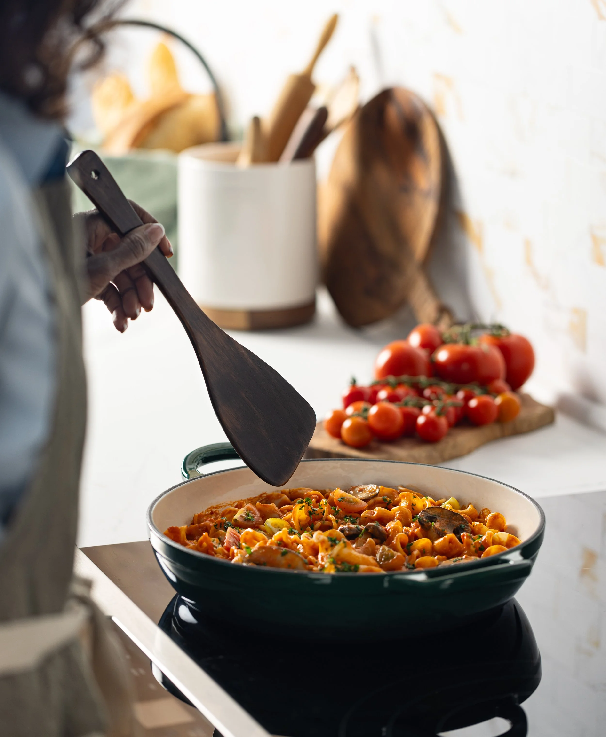 Food photograph of a woman cooking a pasta dish in photo studio kitchen.