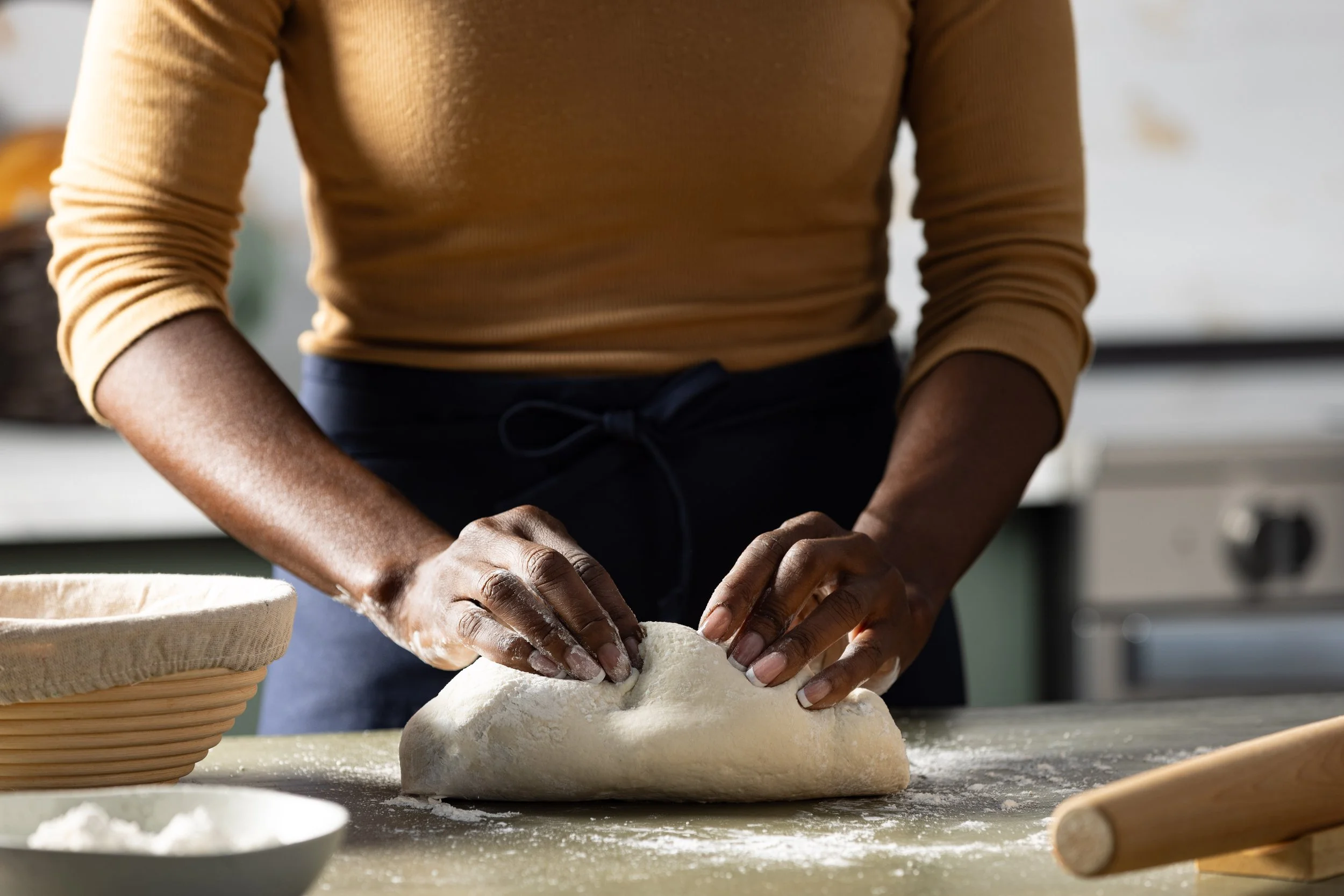 Lifestyle food photograph of a woman kneading some dough in photography studio kitchen.