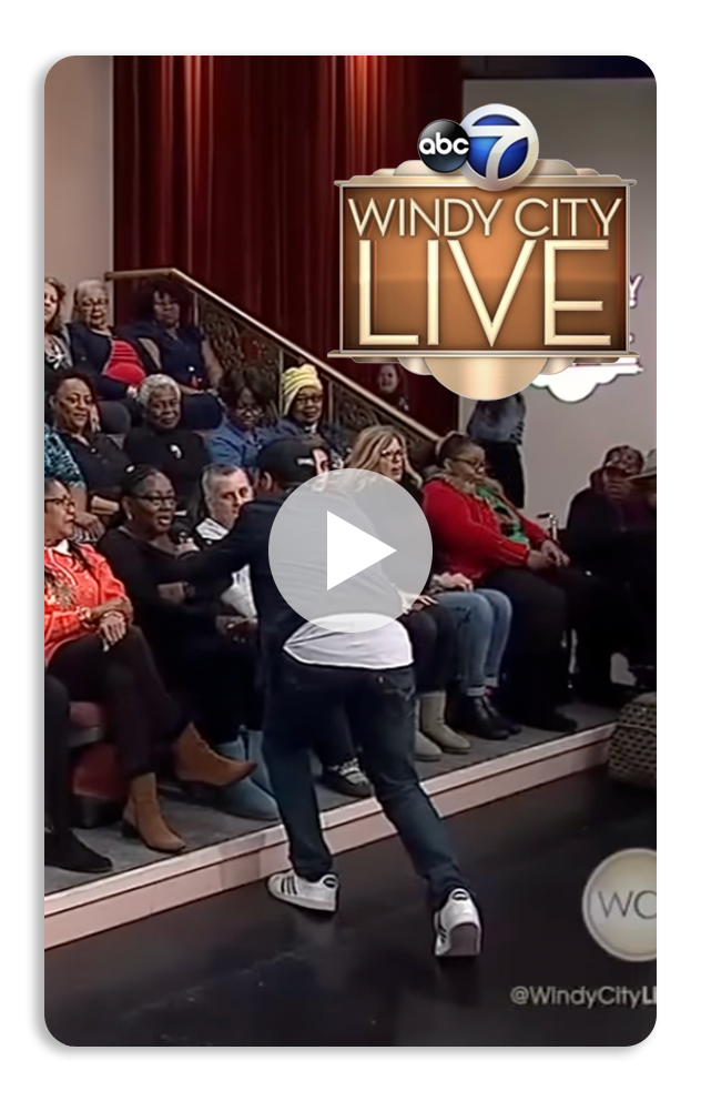 Television broadcast logo of ABC 7 and 'Windy City Live' seen in a studio with an audience, with a person walking across the stage.