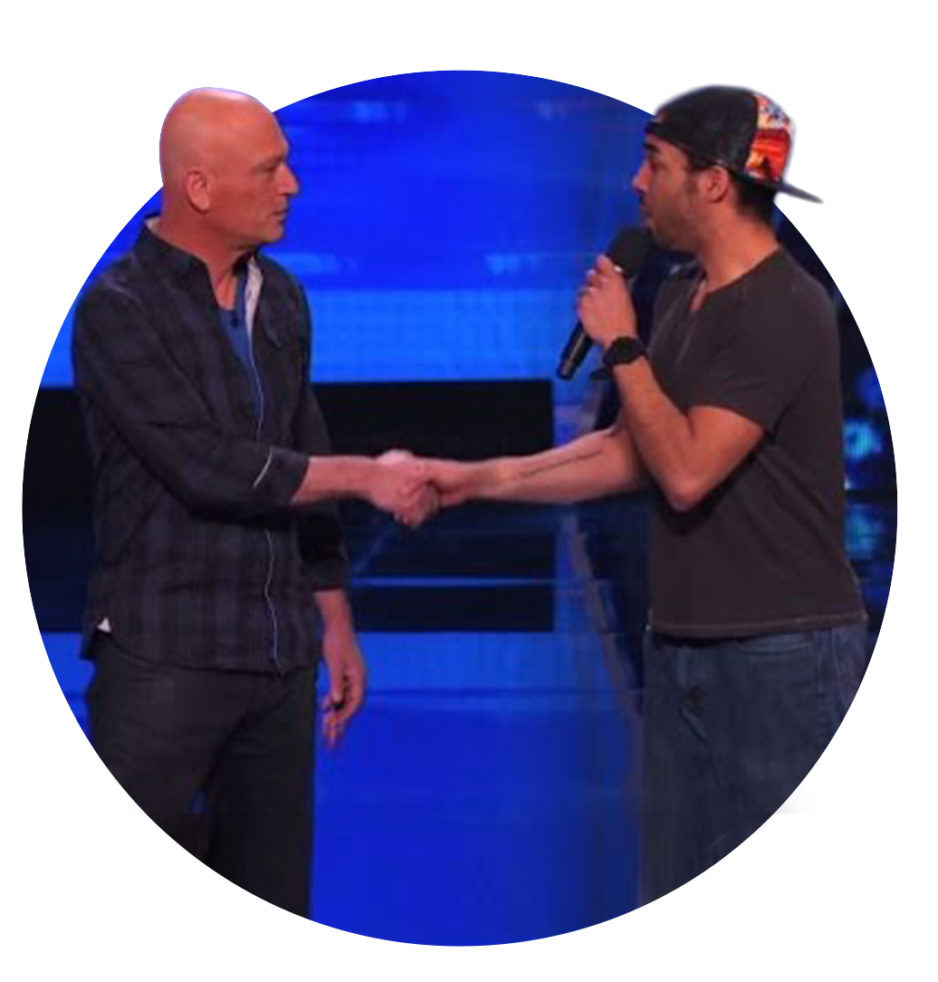 Chrisjones shaking hands with Howie Mandel on stage during America's Got Talent, one holding a microphone.