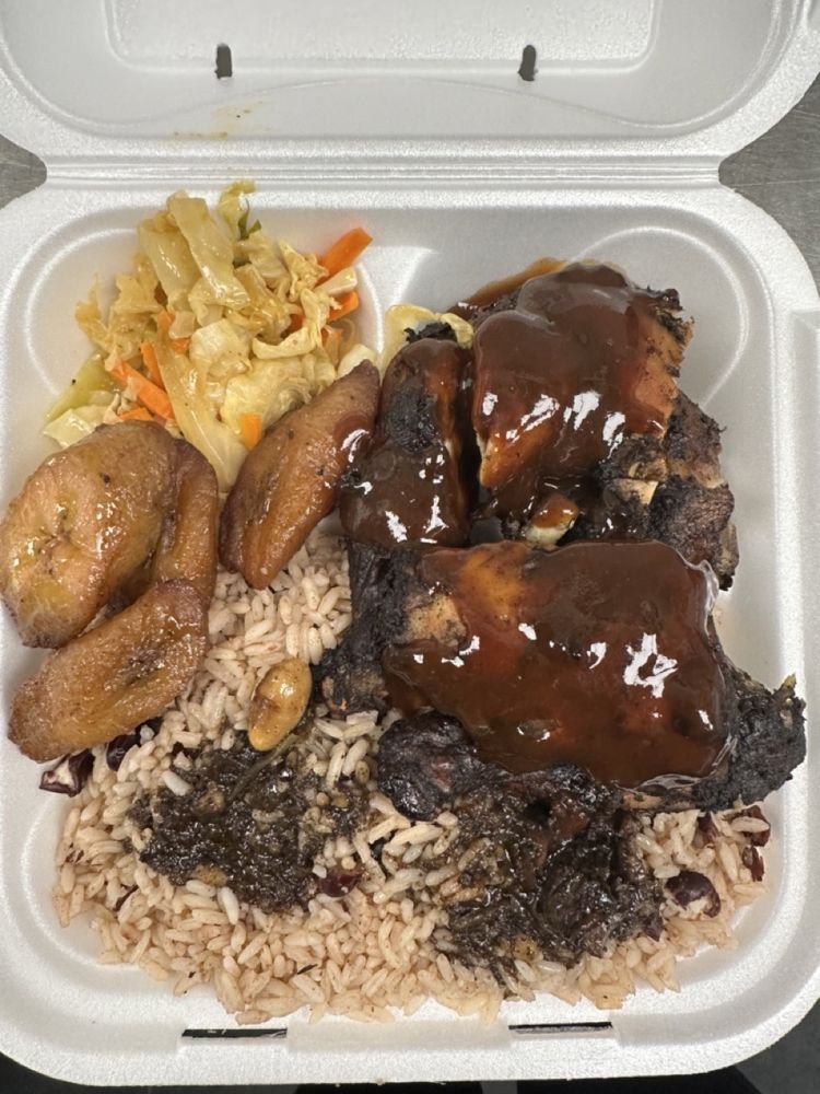 Foam takeout container with barbecue chicken, rice, fried plantains, and a vegetable medley
