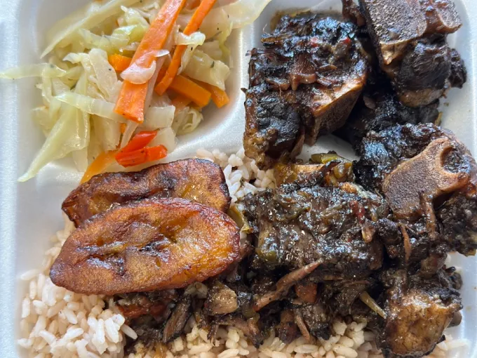 Plate with rice, cooked cabbage with carrots, fried plantain, and beef stew with vegetables.