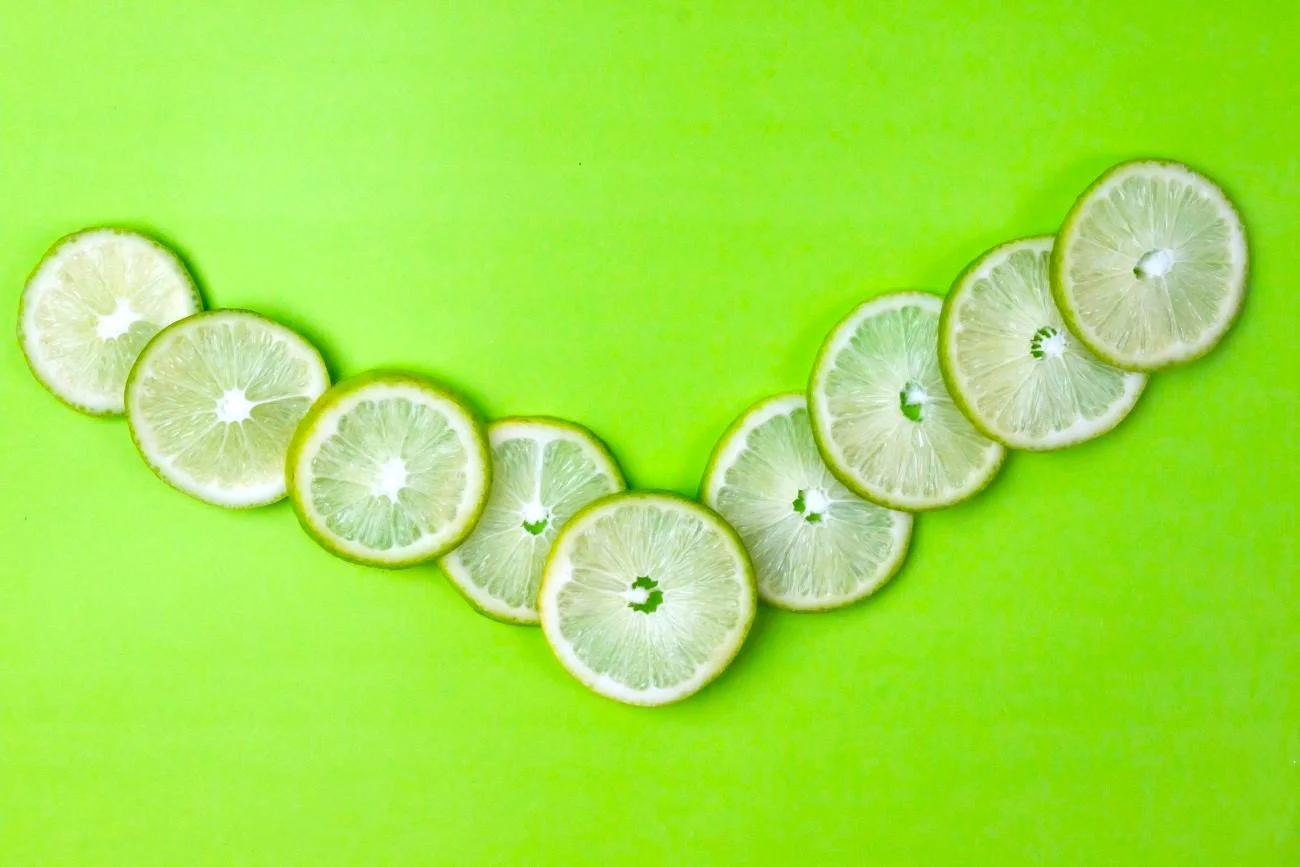 Various lime slices scattered on a light green background