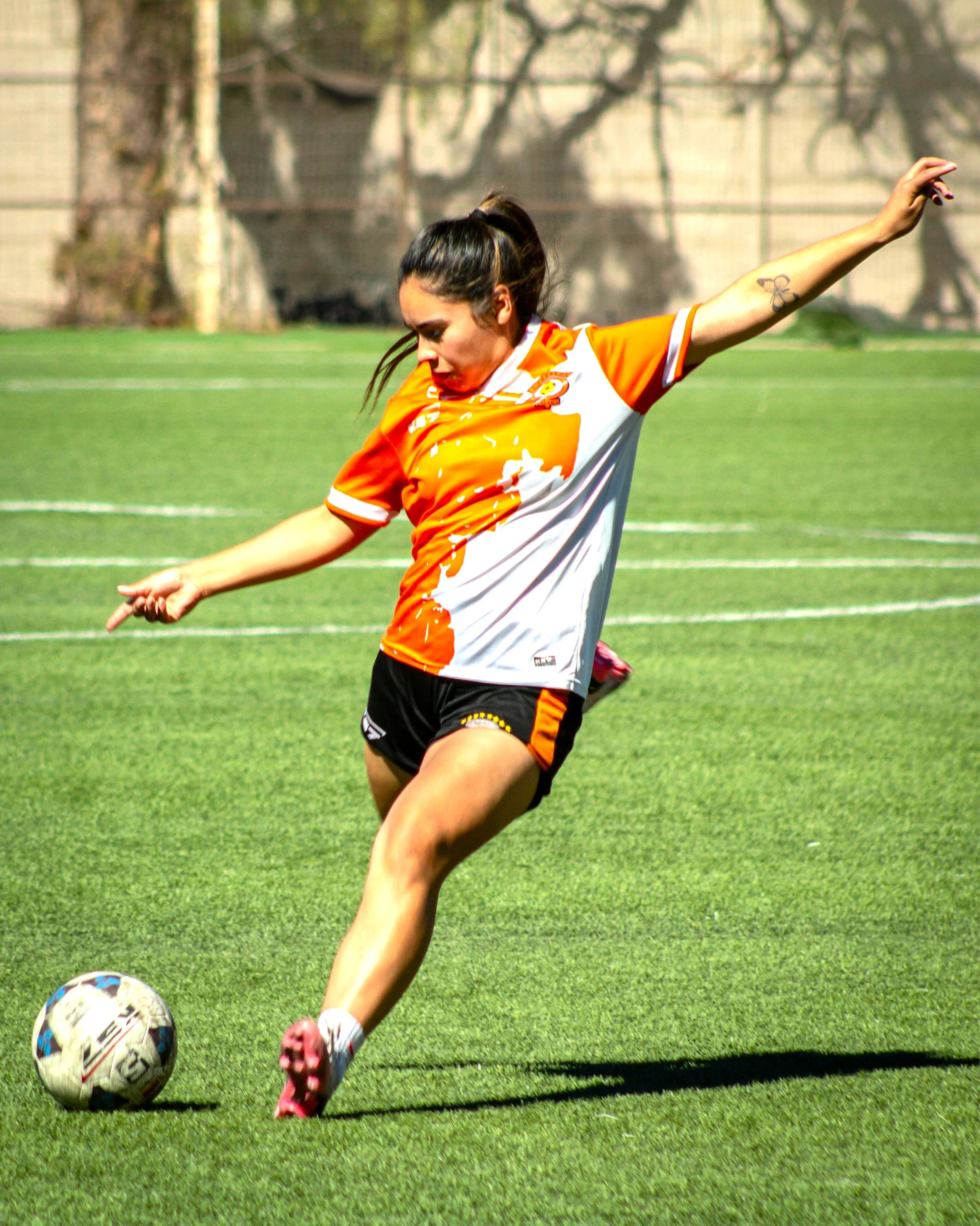 A woman playing soccer kicking a soccer ball