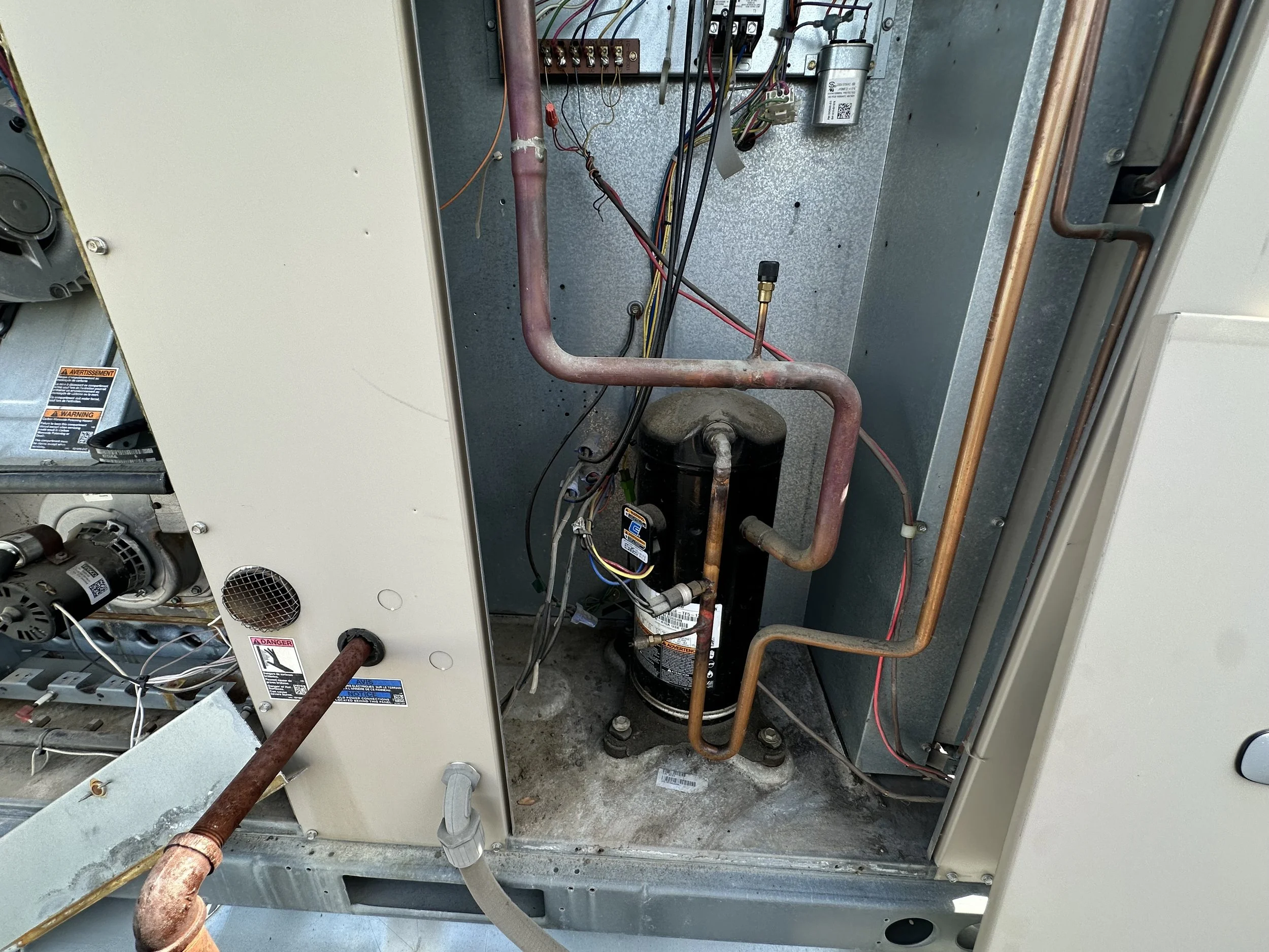 The image shows the internal components of an HVAC unit, including copper pipes, a compressor, electrical wires, and other mechanical parts.