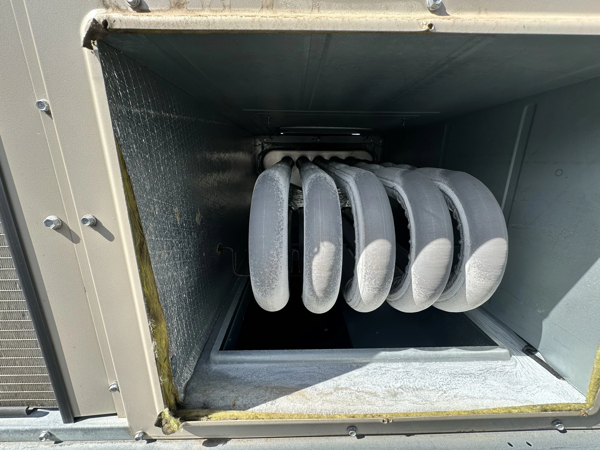 Close-up view of the inside of an air conditioning unit showing the evaporator coil and foam-covered cooling fins.