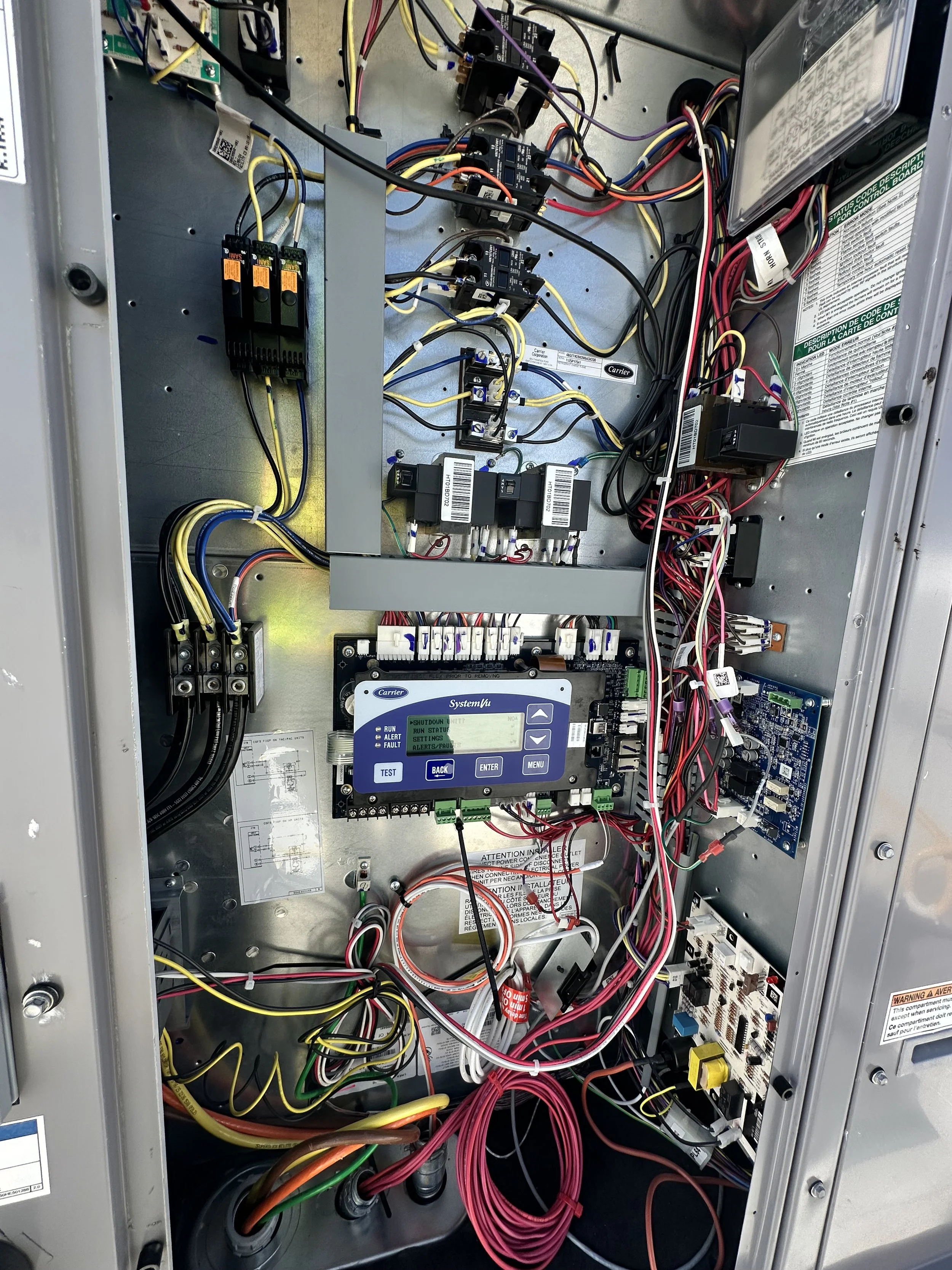 Inside view of an electrical control panel with wiring, relays, circuit boards, and a digital controller.