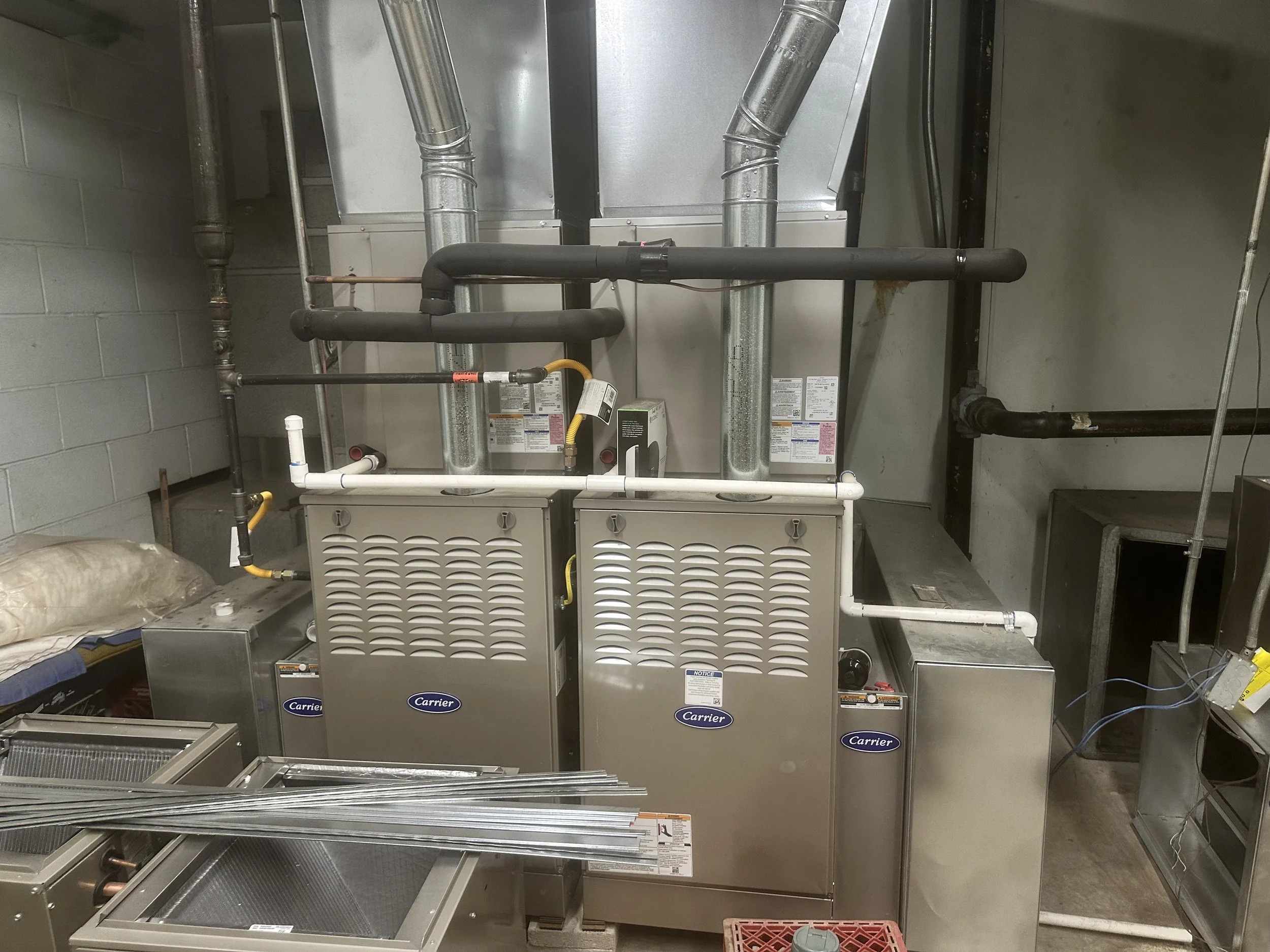 Industrial refrigeration units with pipes and ducts in a mechanical room.