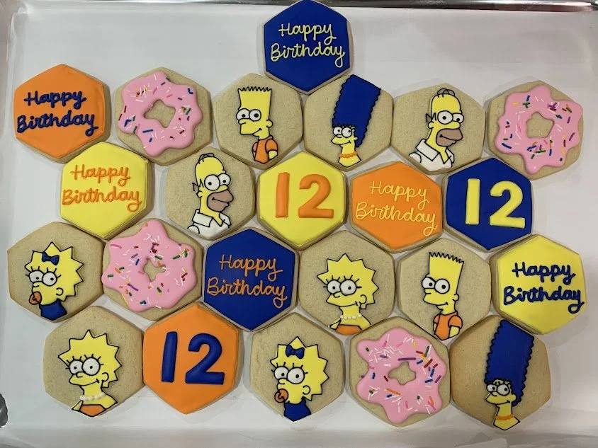 Decorated cookies on a tray with cartoon characters, birthday messages, and the number 12 in bright colors for a birthday celebration.