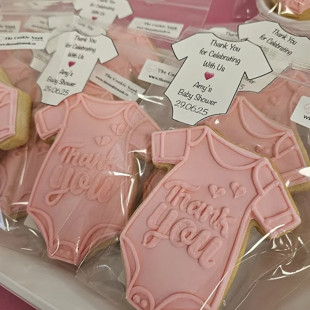 Decorated cookies in pink onesie-shaped boxes with 