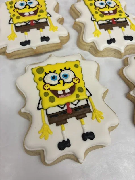 Cookies decorated with SpongeBob SquarePants design, featuring SpongeBob's face, yellow sponge body, blue eyes, and brown pants.