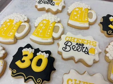 Decorated cookies celebrating a 30th birthday, with beer mug and beer bottle designs, in yellow, white, and black colors.