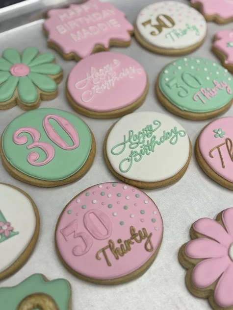 Decorative cookies with pink, white, and mint green icing, featuring birthday messages and number cakes for celebrating a 30th birthday.