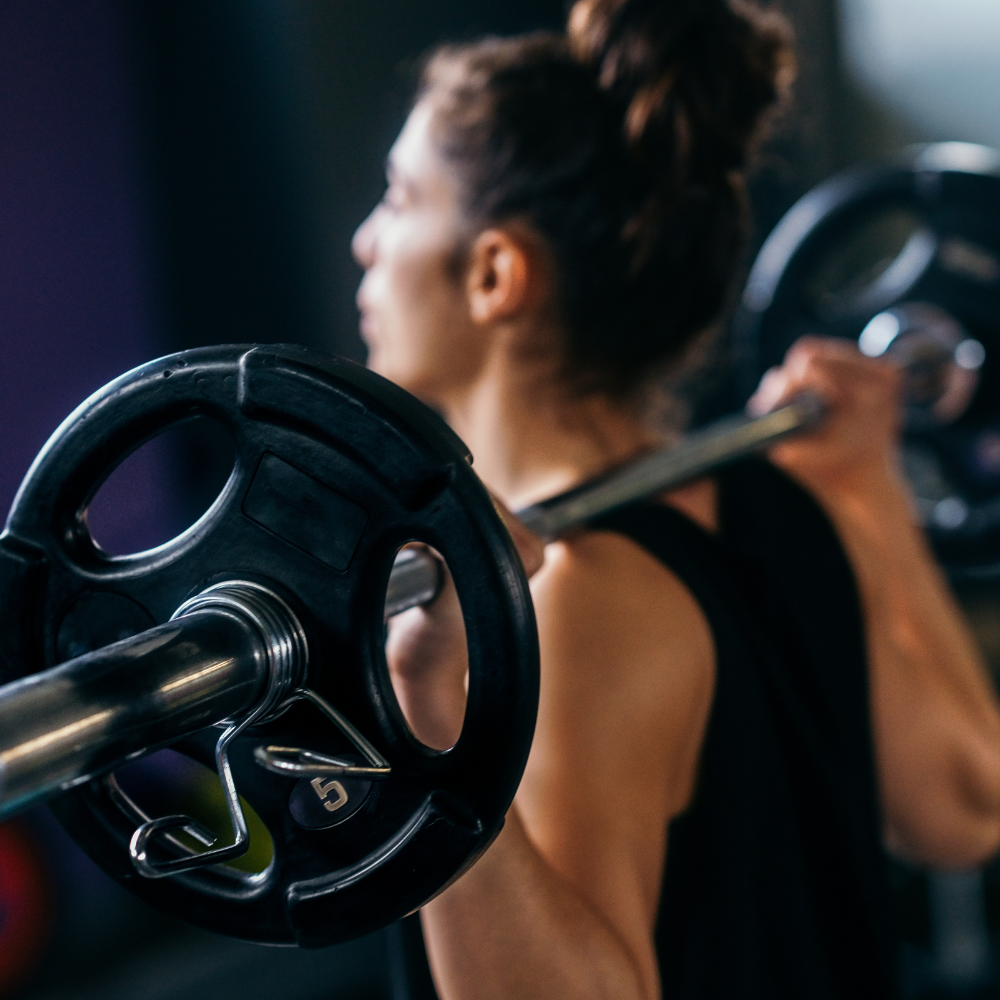 Close-up of a woman lifting a barbell in a gym.