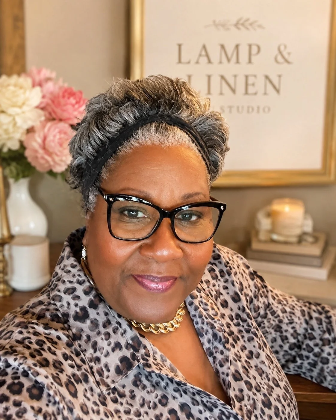 Portrait of the Lamp & Linen Studio founder wearing black glasses and a patterned top in her home studio.