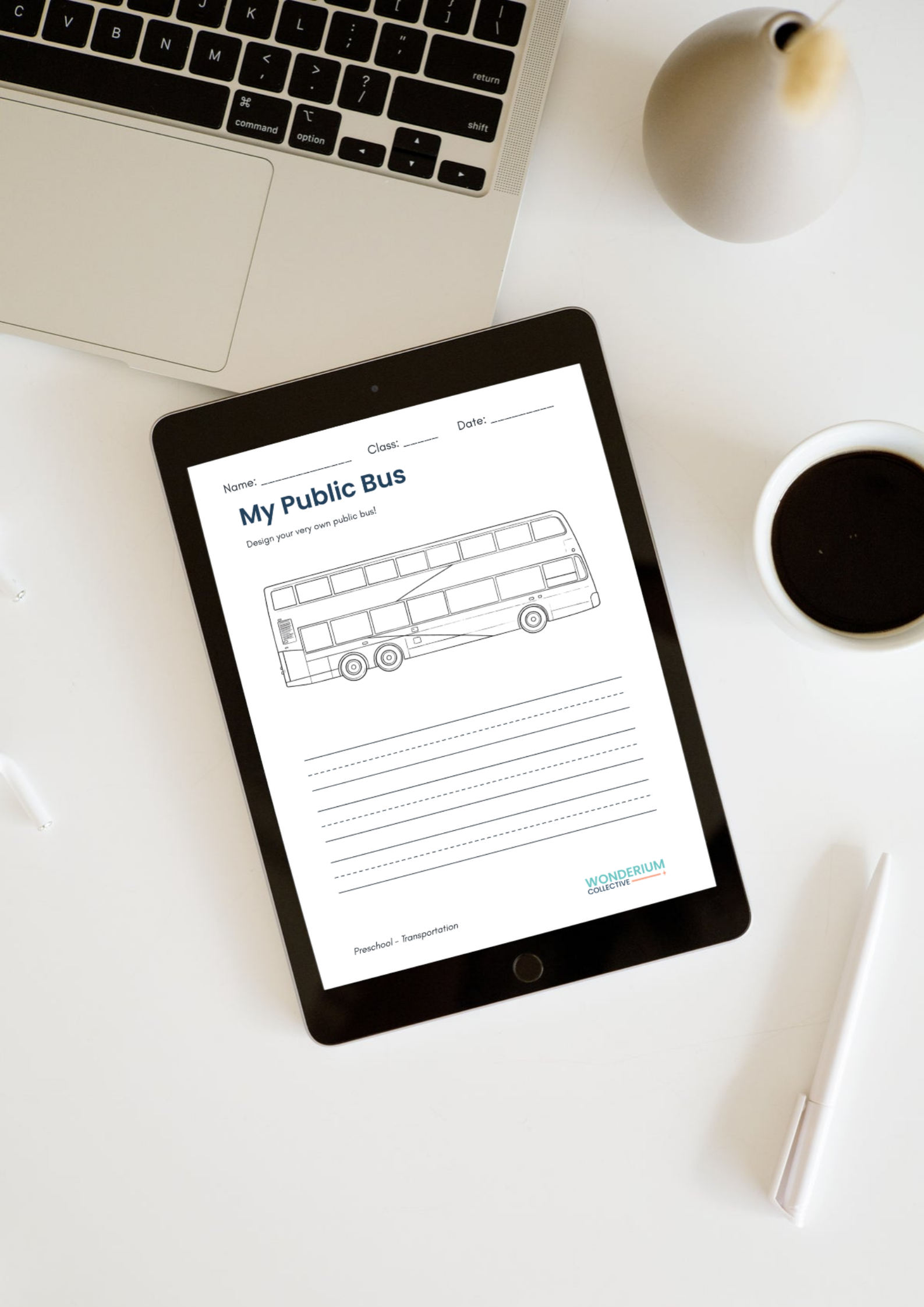 A flat lay of a workspace with a MacBook, a tablet with a drawing of a bus titled 'My Public Bus,' a white pen, a cup of black coffee, and a gray decorative object on a white surface.