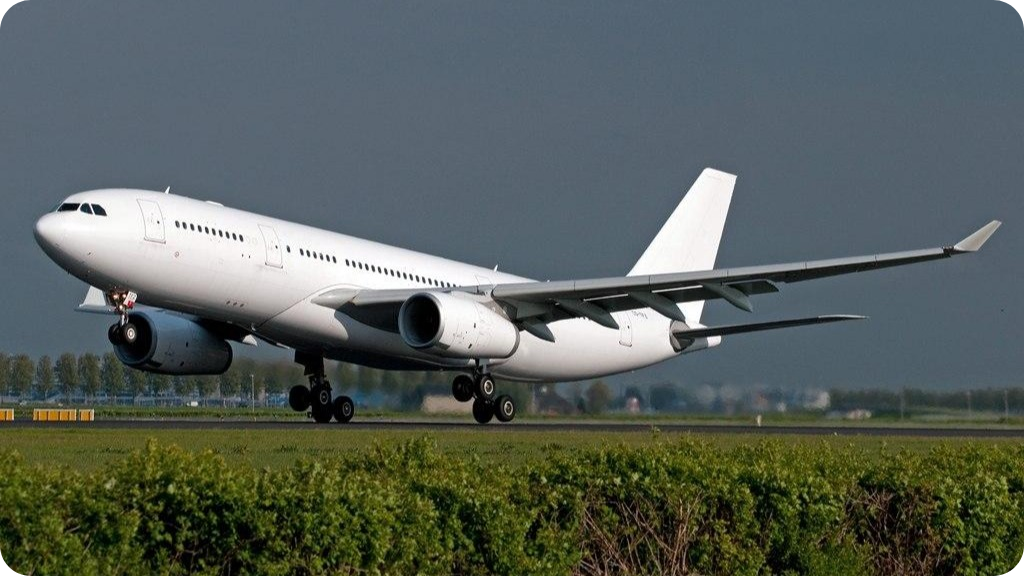 A large white commercial airplane landing on a runway with a gray cloudy sky.