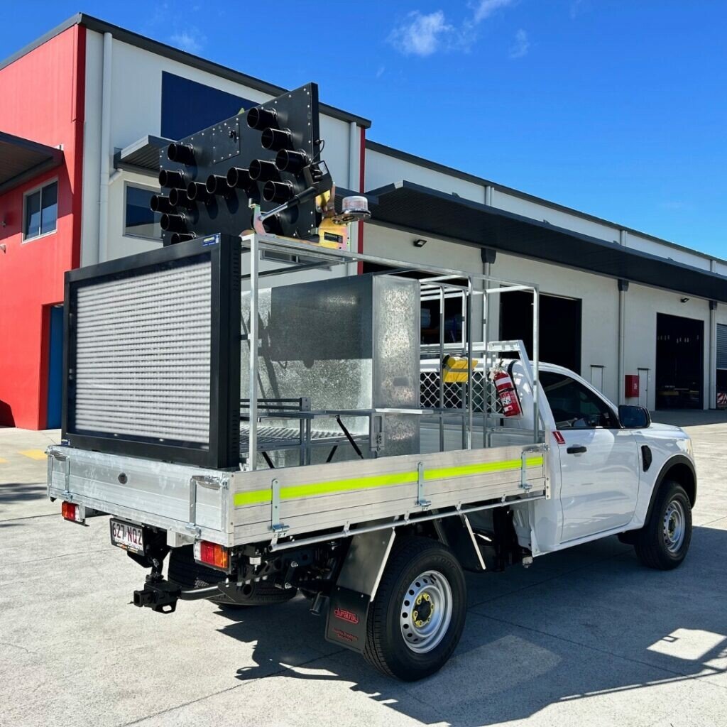 Safety vehicle with a large black device and fire extinguisher mounted on a truck outside a building with a red and white exterior.