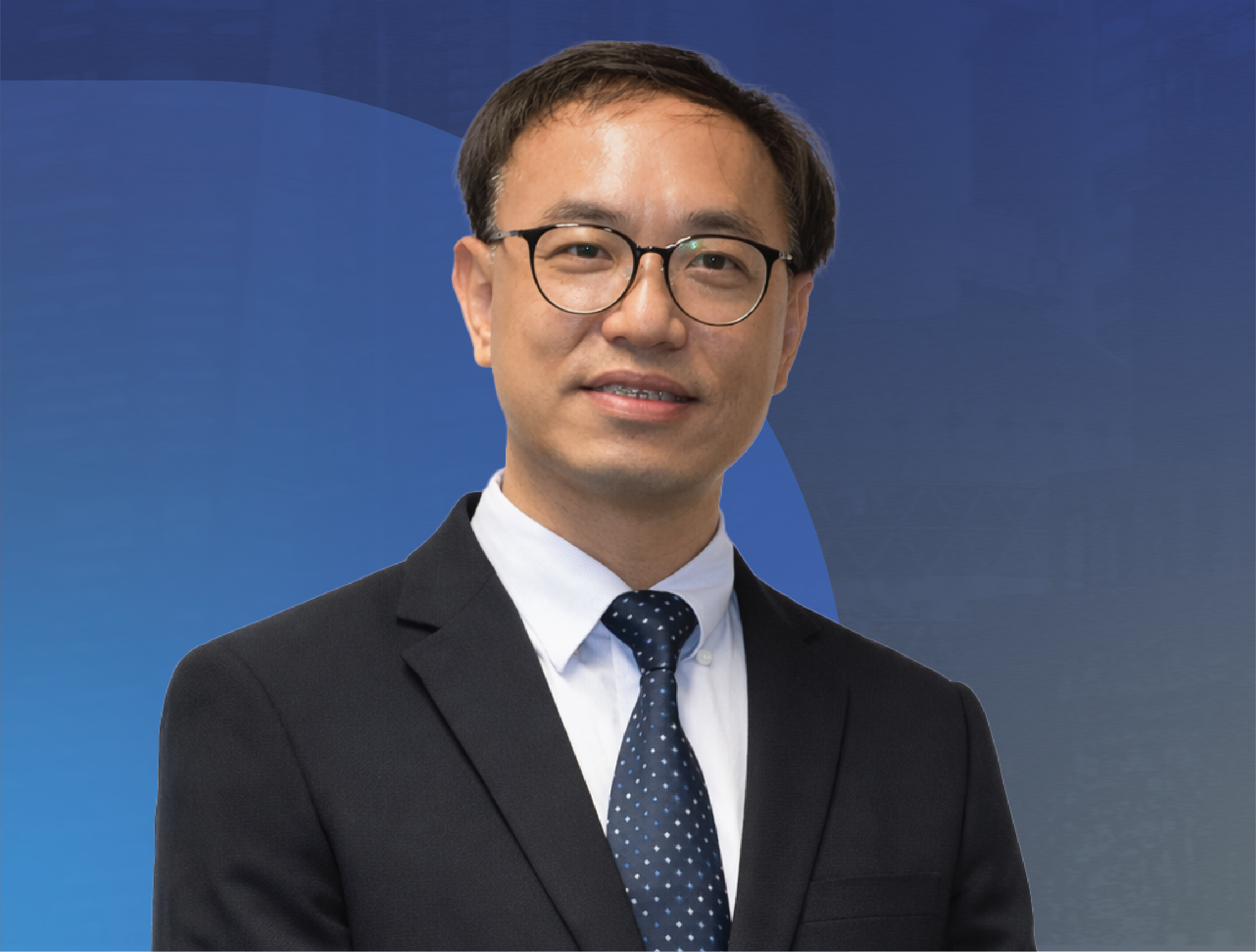 Professional portrait of Professor Kenneth Fong from Hong Kong Polytechnic University wearing glasses, a dark suit, white shirt, and a blue polka-dot tie, standing against a blue abstract background.