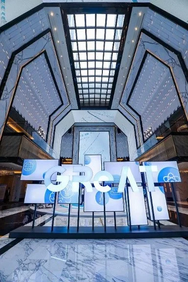 Interior view of a modern building with a high glass ceiling and large LED displays showing the letters 'GPC' and the word 'GOPAS' in a well-lit, spacious lobby.