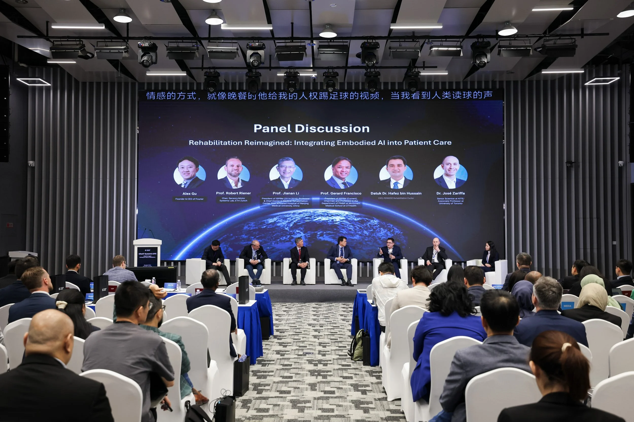A conference room with a panel discussion on stage titled 'Rehabilitation Reimagined: Integrating Embodied AI into Patient Care.' The panel features six speakers seated in chairs, with a large screen behind them displaying photos and names of the pan