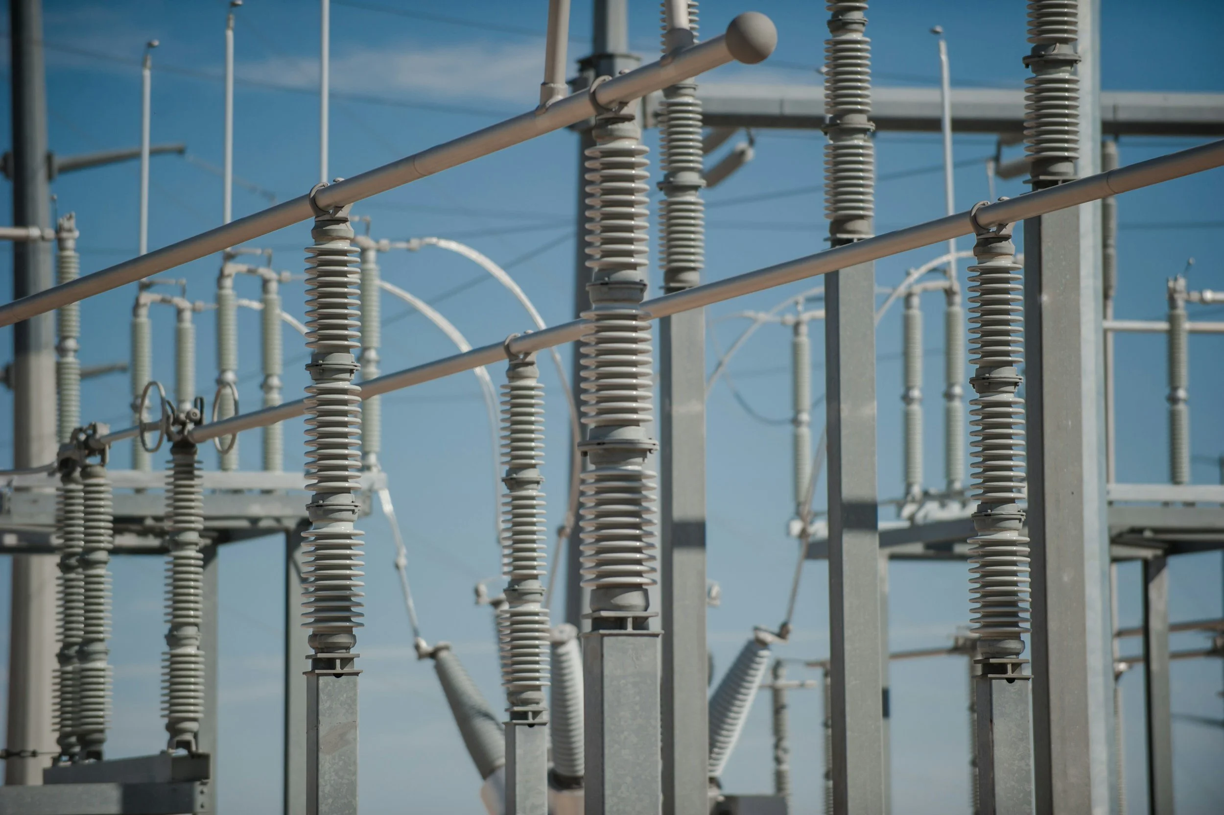 Close-up of electrical insulators and power lines on a clear day with a blue sky.