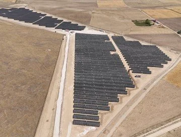 A large solar farm with multiple rows of solar panels installed on a flat, open area of land.