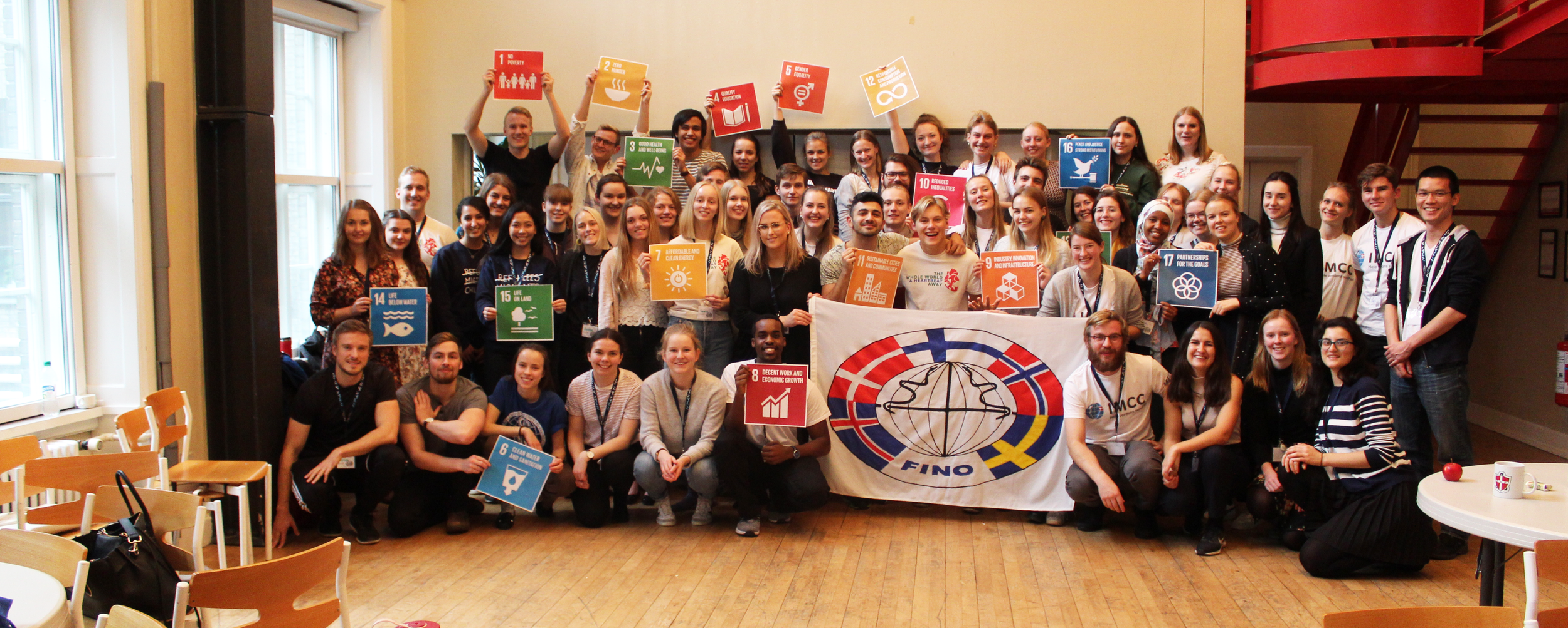 Billede fra en international konference. Gruppe af unge mennesker, mange holder flag fra forskellige lande.