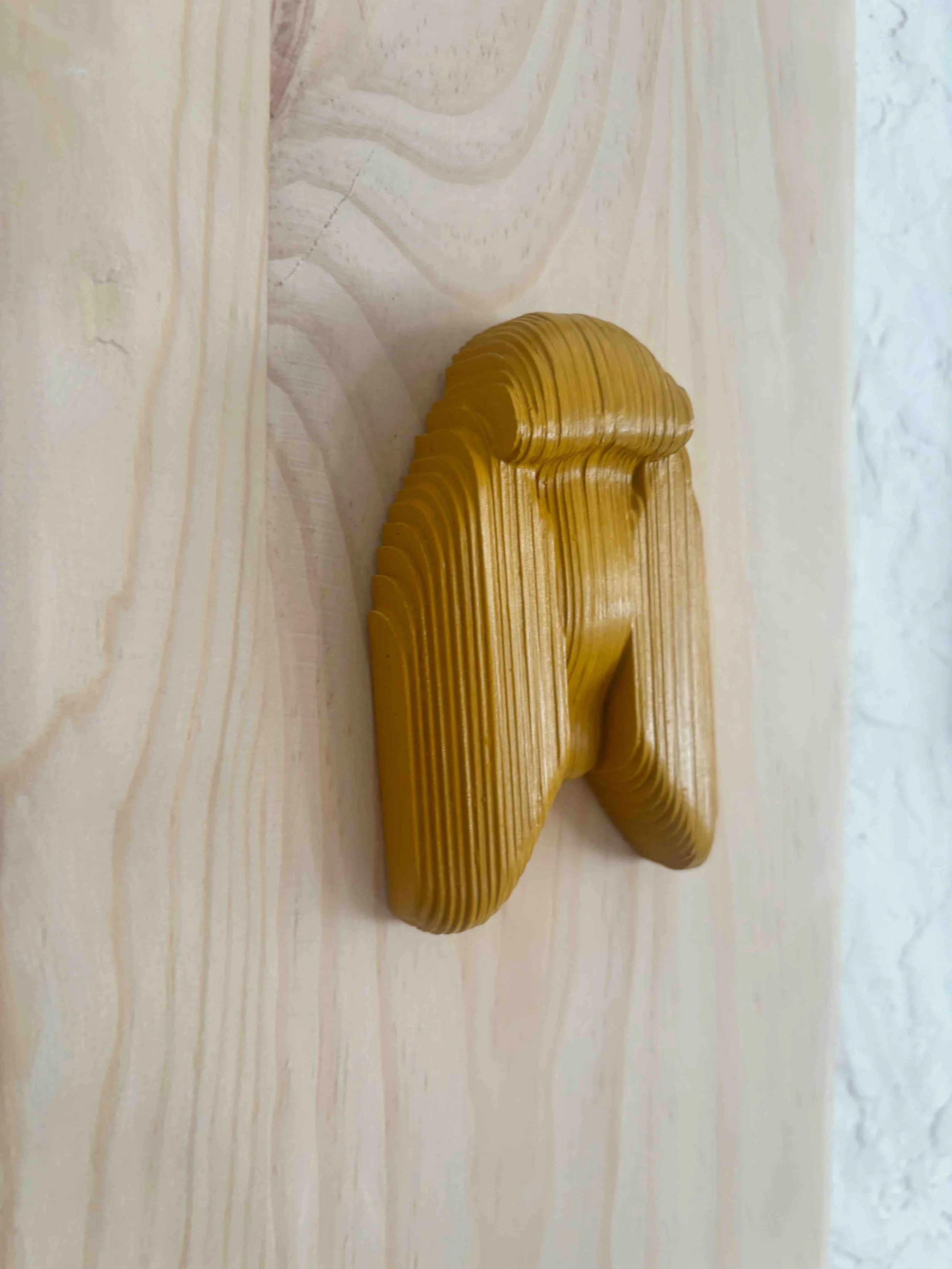 Un ruban de scie en bois en forme de clé, jauneâtre, posé sur une surface en bois clair.