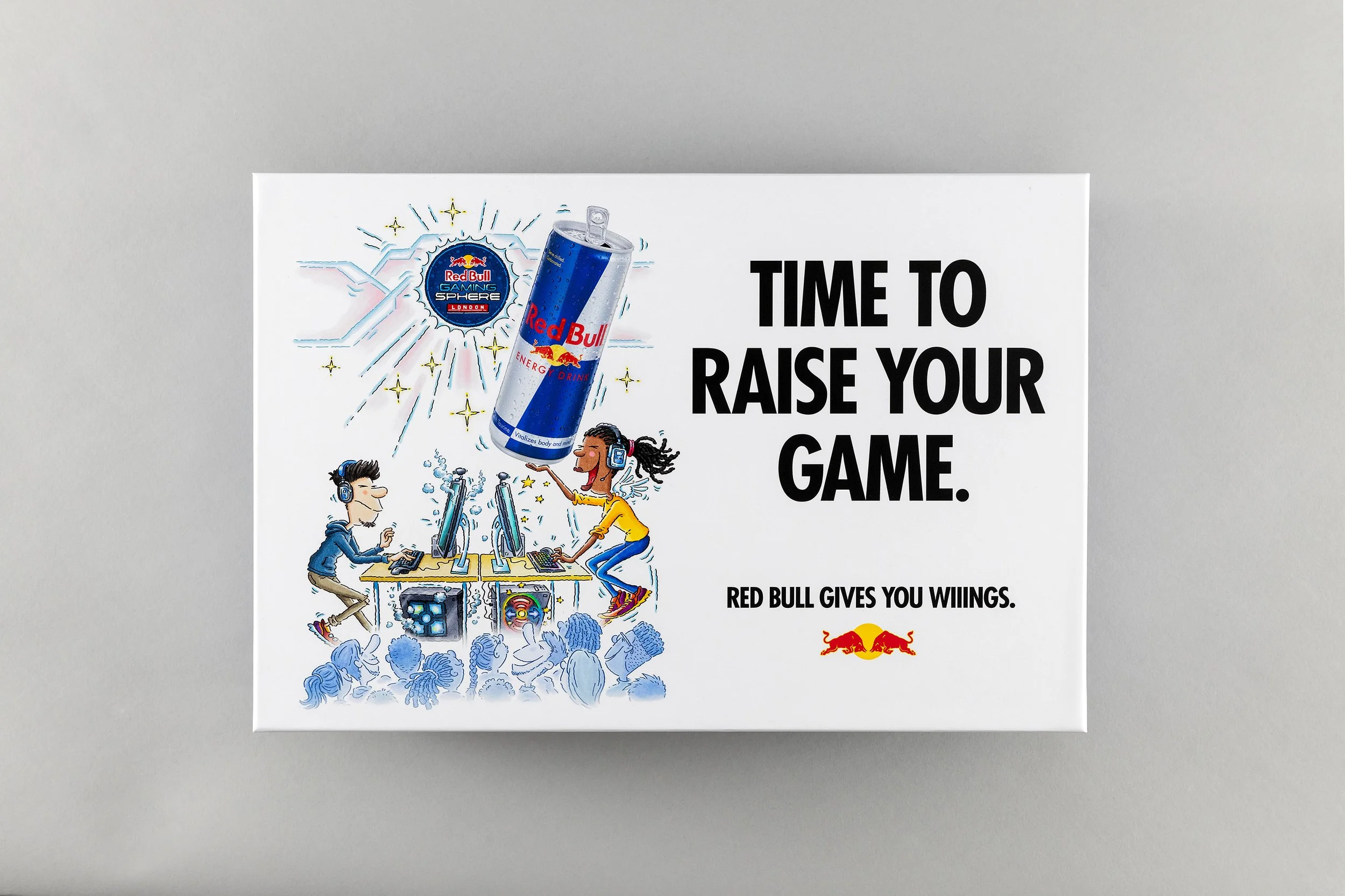 Illustration of a gaming scene with two players at computers, and a large Red Bull energy drink can above them, with the Red Bull logo and the words 'Red Bull Gaming Sphere London'. The scene includes a crowd watching and a logo of Red Bull with a sl