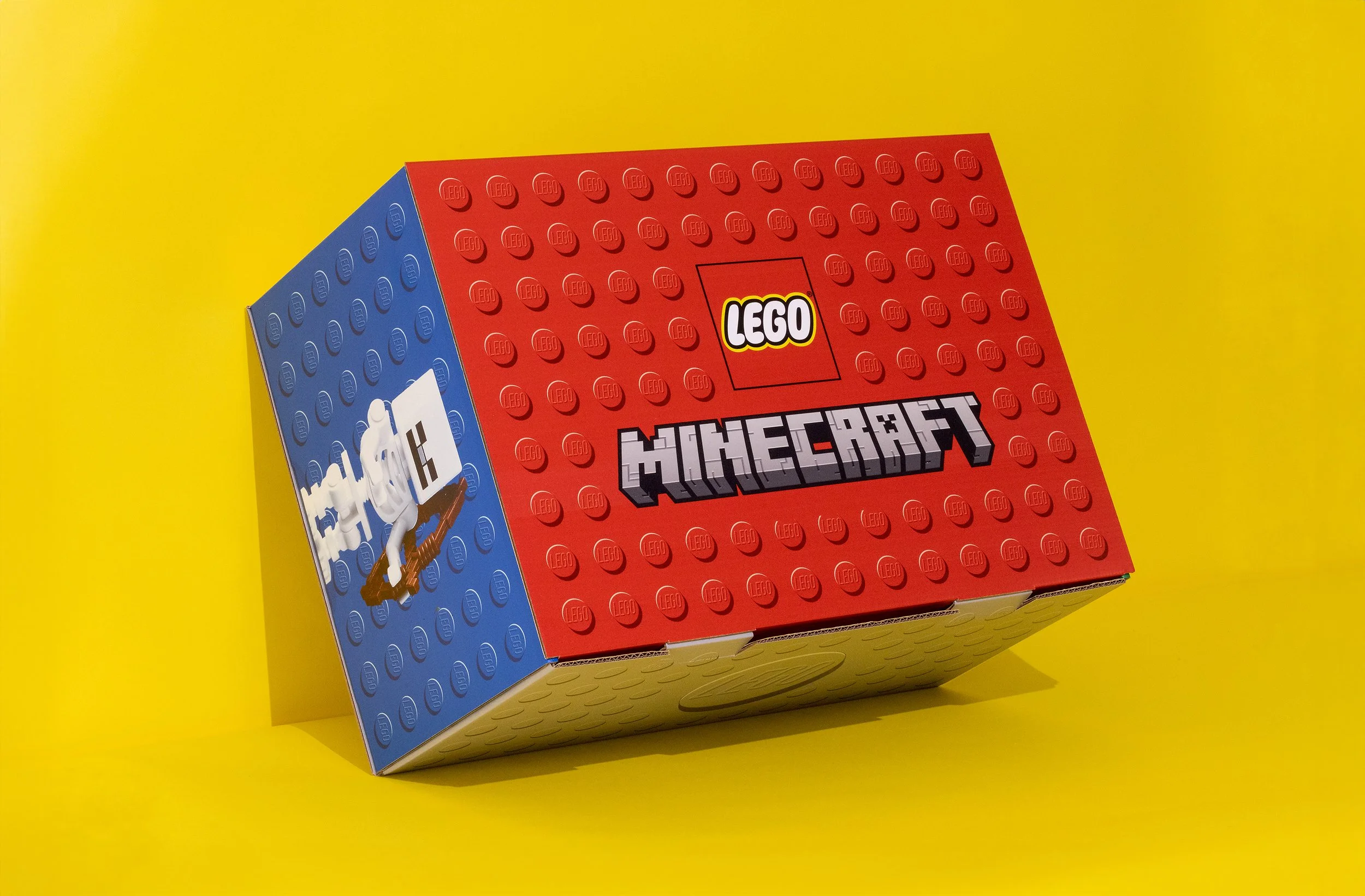 Lego Minecraft set box with red and blue background, sitting on a yellow surface.